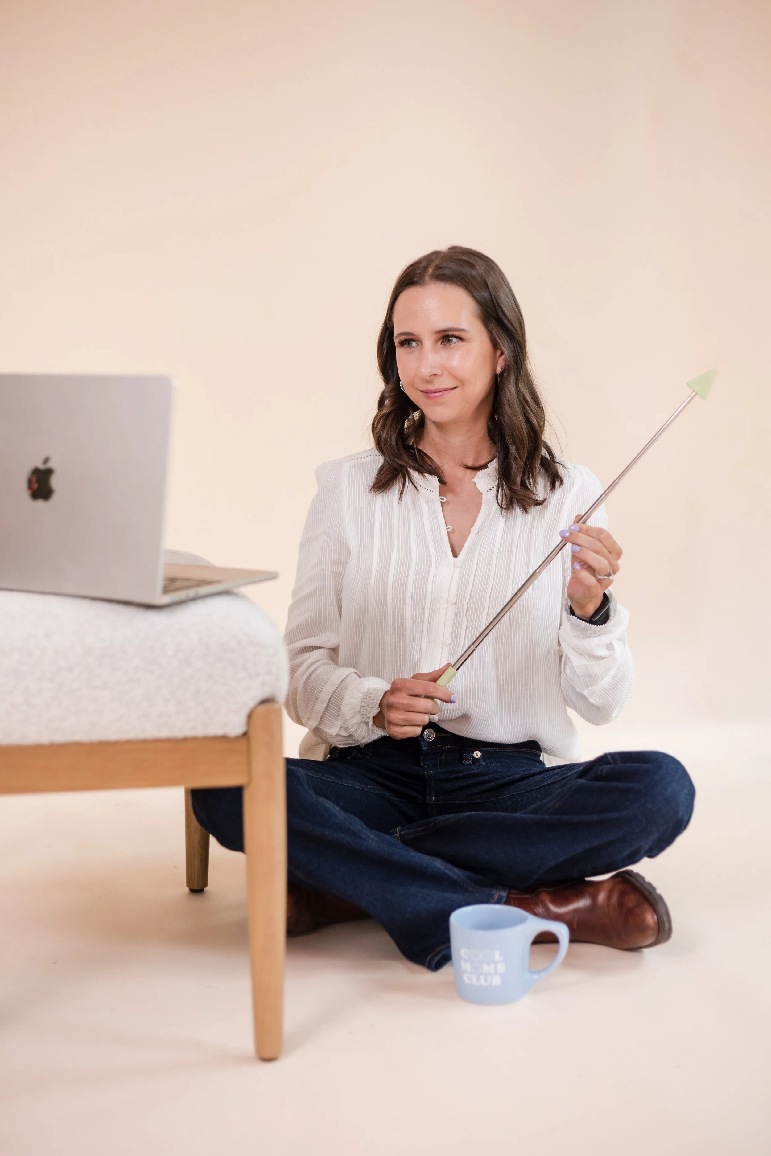 brainspotting therapist brittany sallaberry sitting on the ground smiling facilitating brainspotting therapy online in california over her laptop propped on a chair in front of her