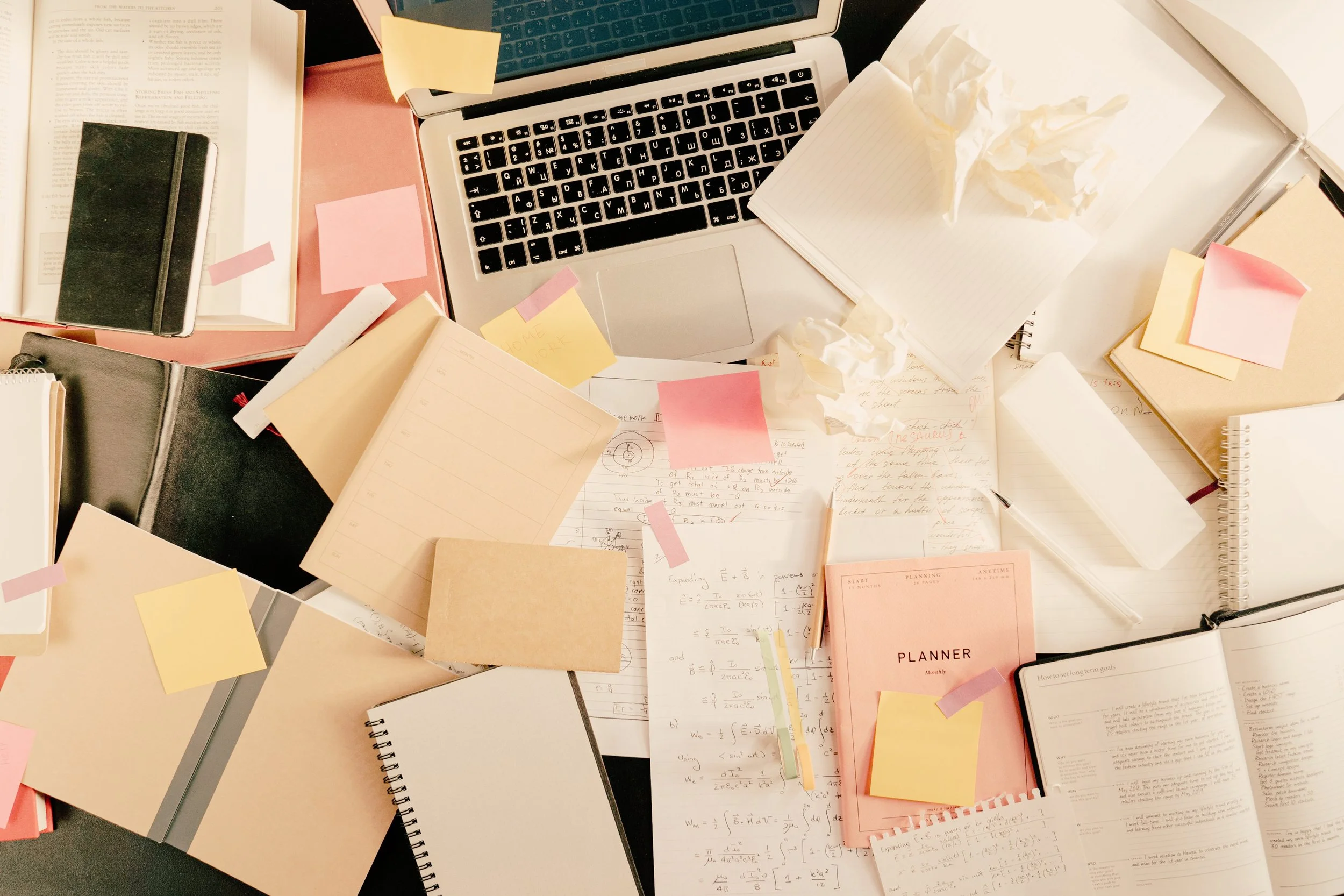 cluttered desk with planners