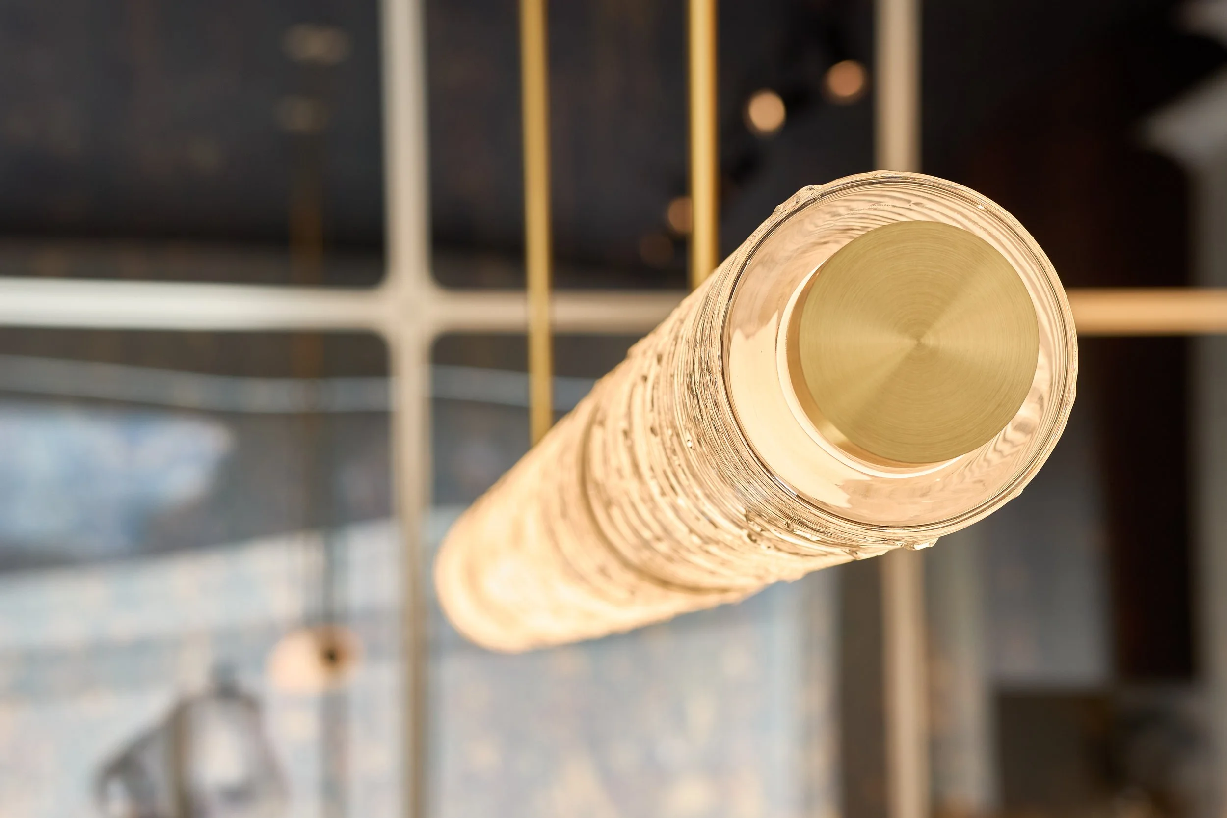 A tall, transparent glass with a gold-colored lid, viewed from above, on a metal wire rack.