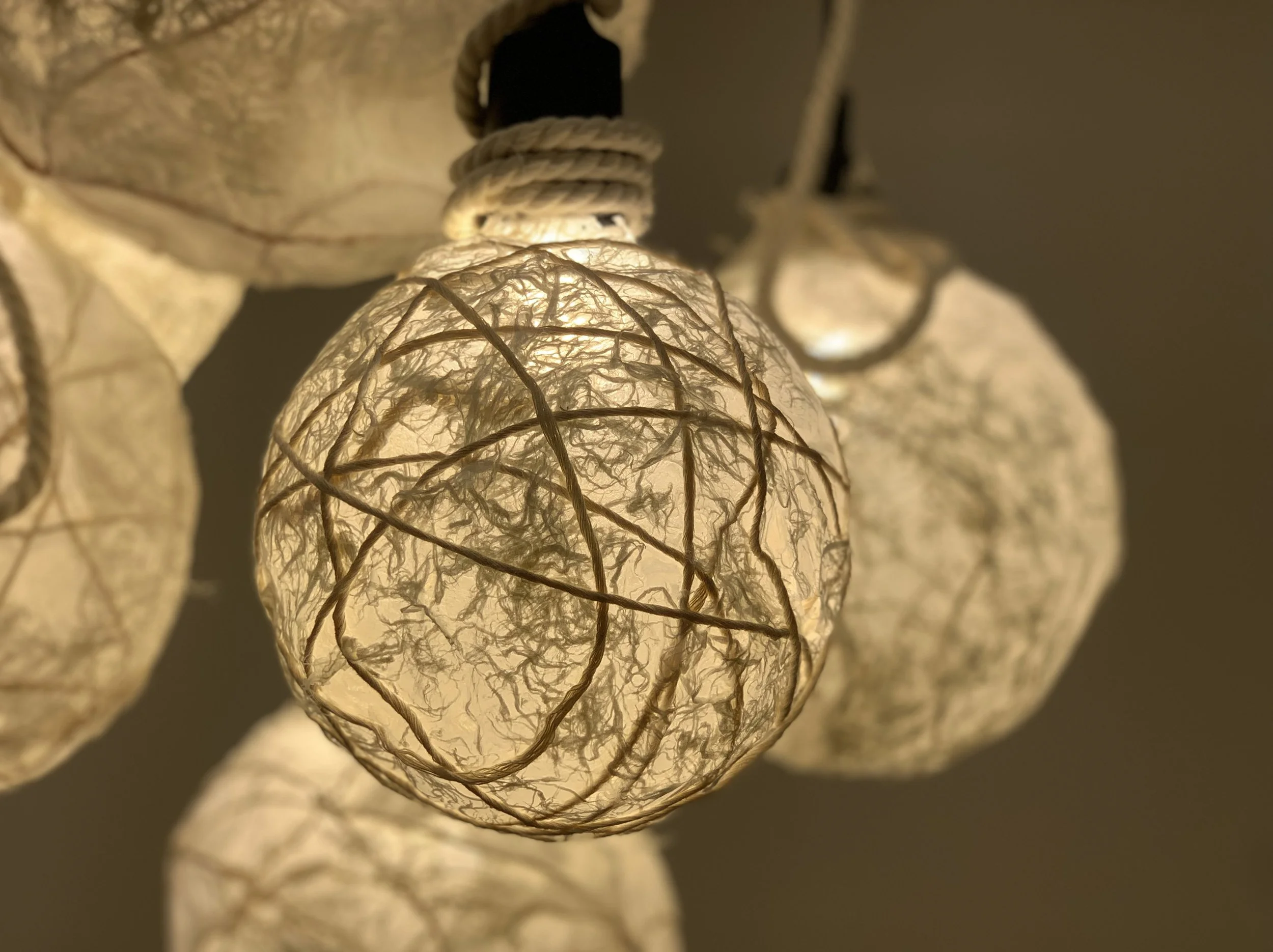 Close-up of illuminated string lights with decorative, spherical paper lantern covers.