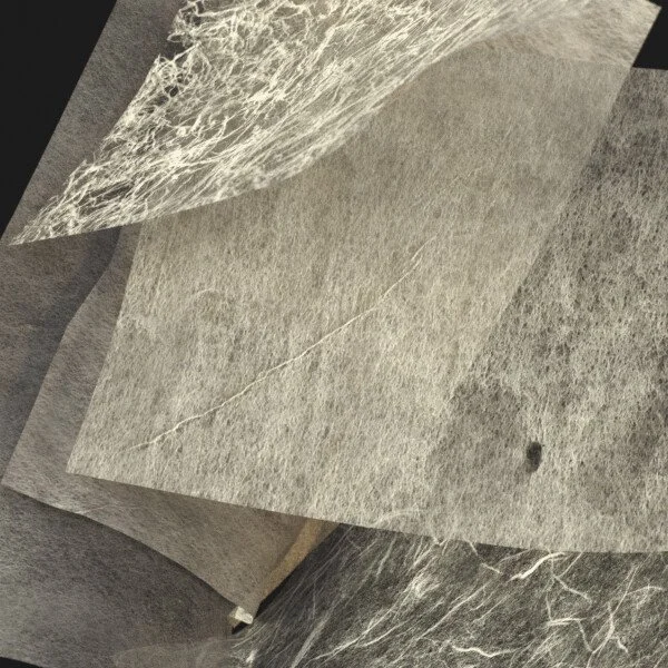 Close-up of layered sheets of textured paper or material with a rough surface and visible fibers.