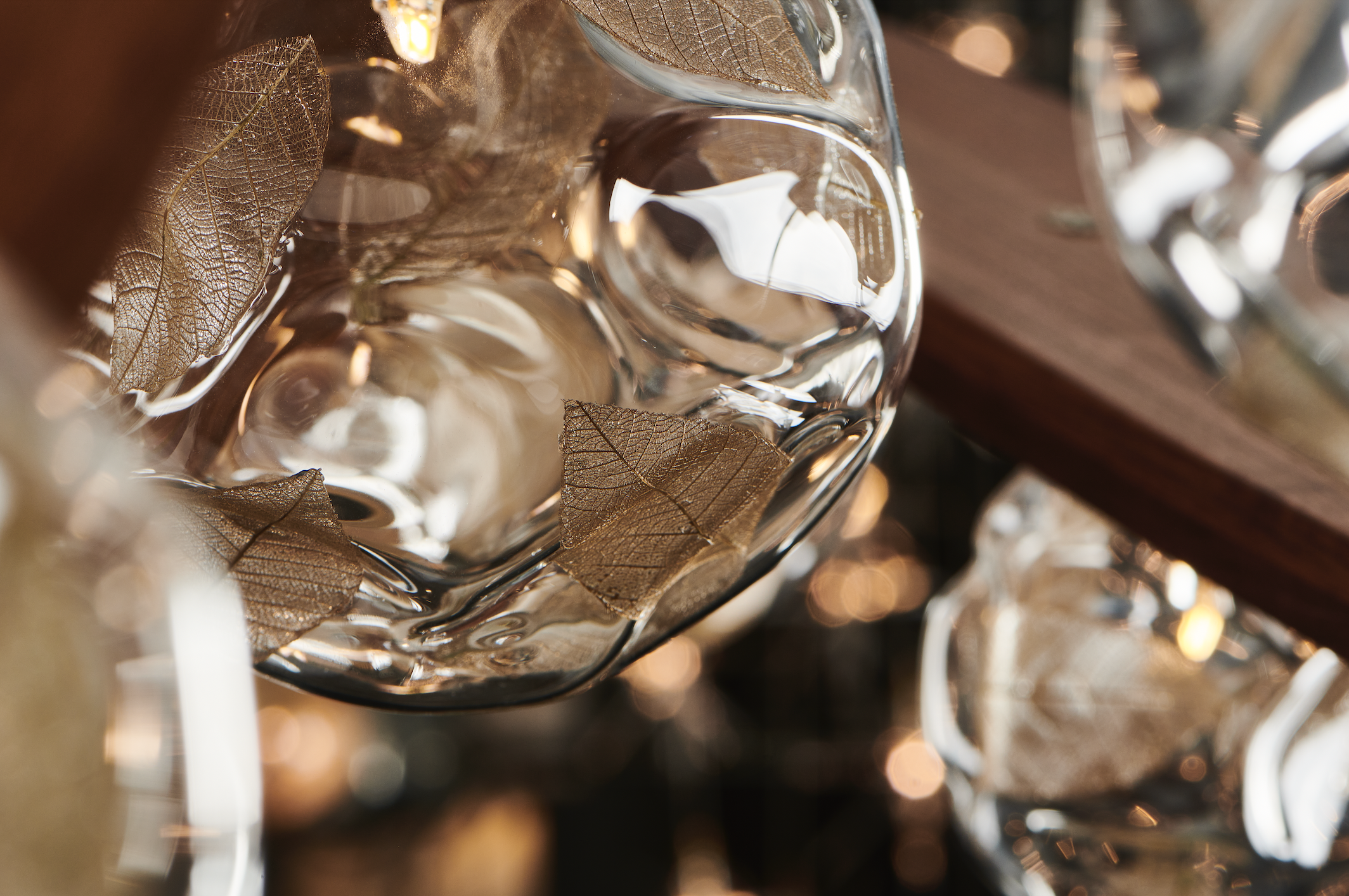 Close-up of a glass with dried brown leaves inside, reflecting light.