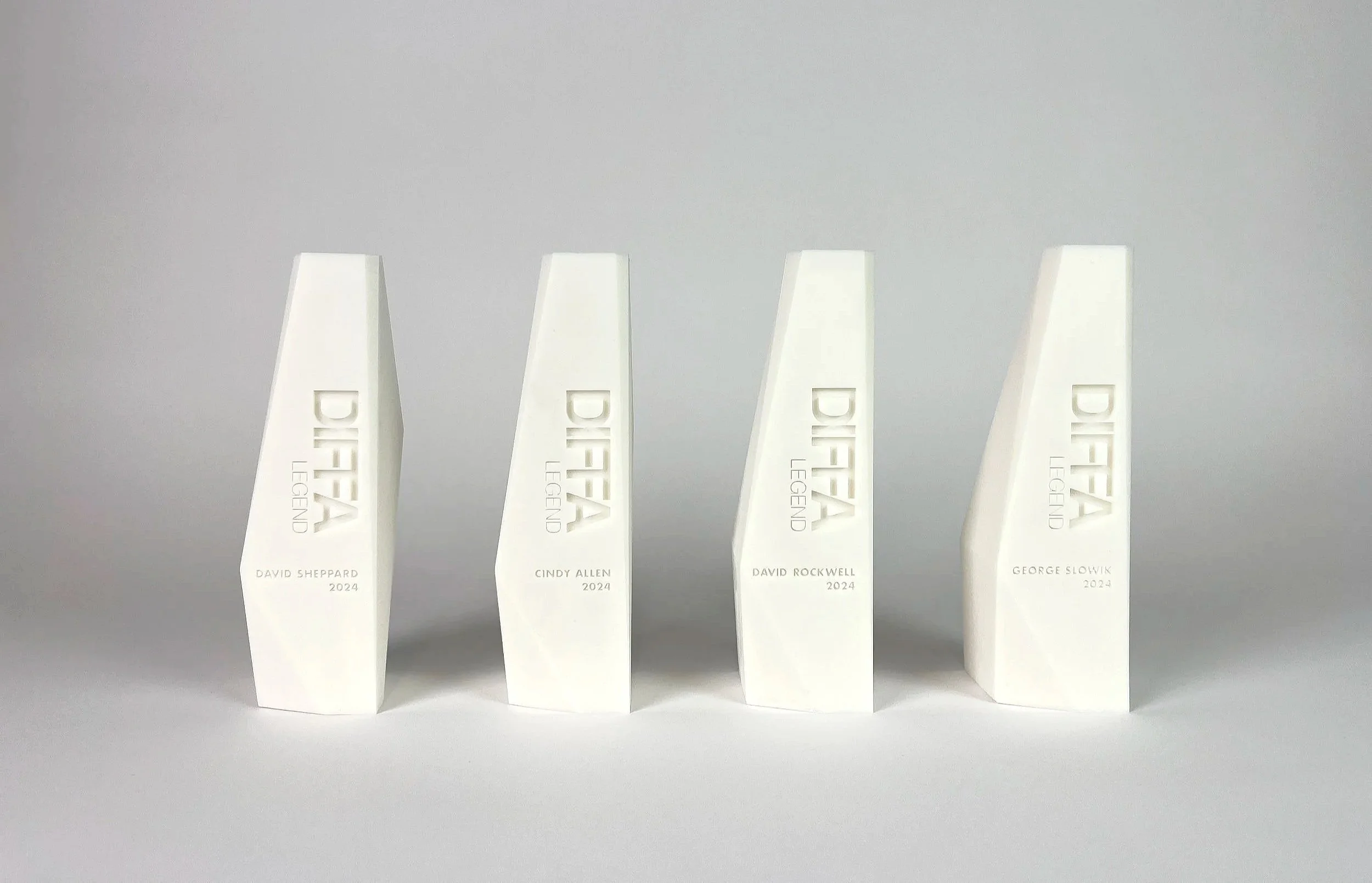 Four white sculpture awards with the words DIFA LEGEND and the names David Sheppard, Cindy Allen, David Rockwell, and George Sloik, all labeled for the year 2024.