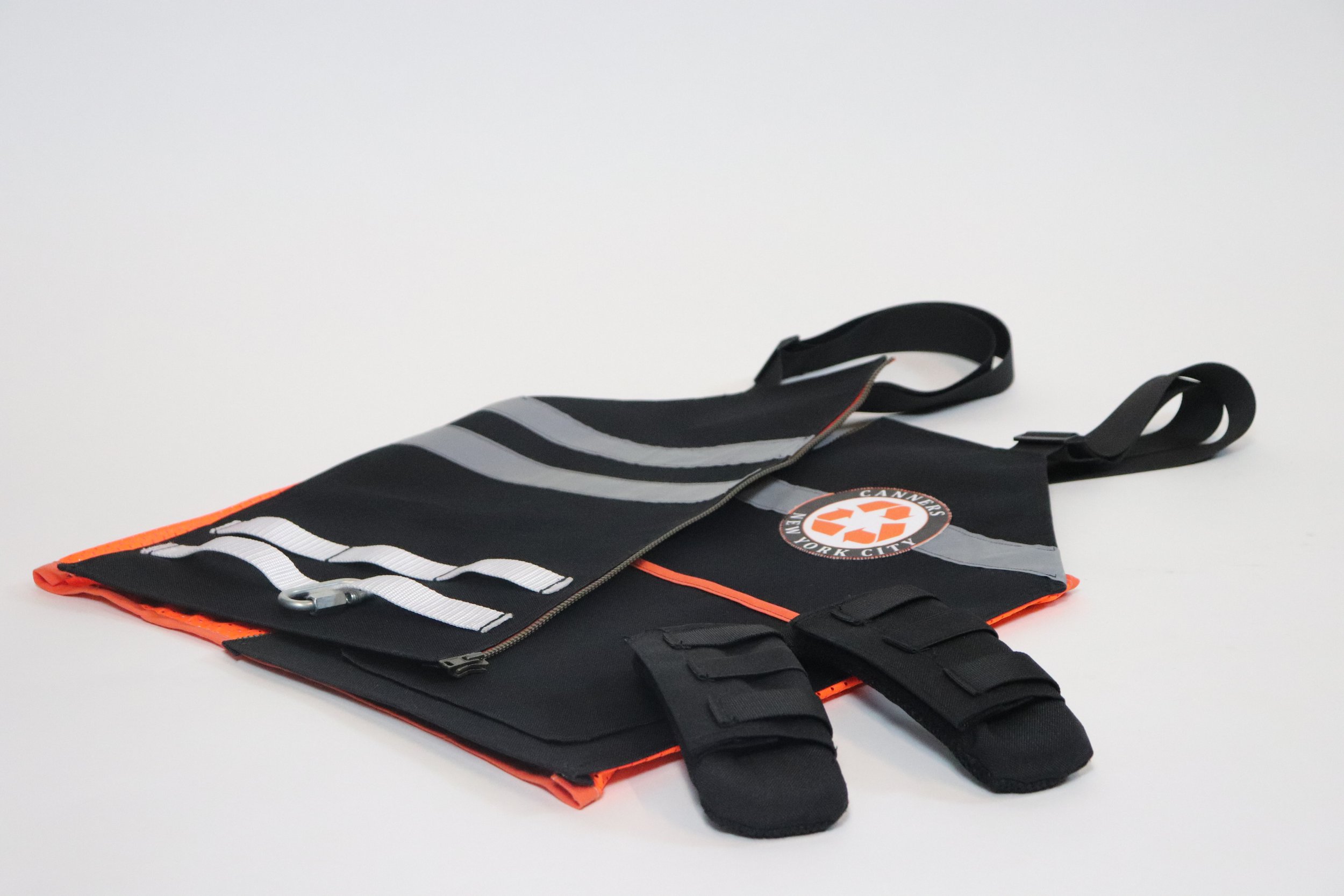 A black safety vest with reflective stripes and a New York City emergency services logo, laid flat on a white background.