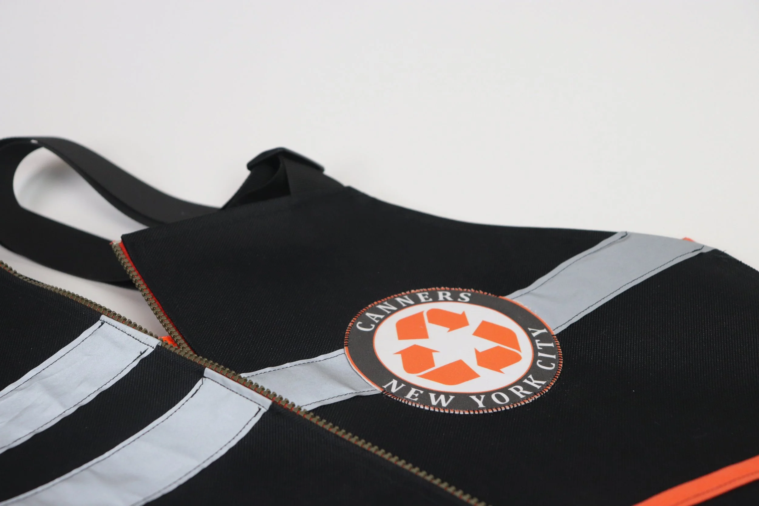Close-up of a black and gray reusable bag with a circular logo of Cameners New York City, featuring orange recycling symbols.