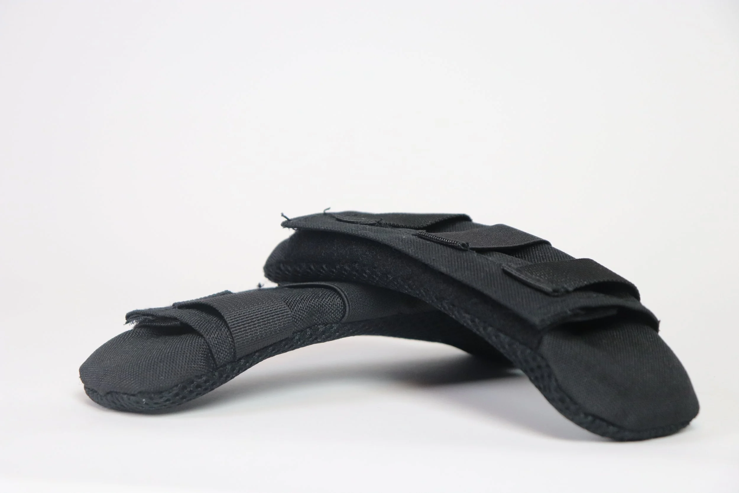 A pair of black tactical gloves with padded fingers and adjustable straps, lying on a white background.
