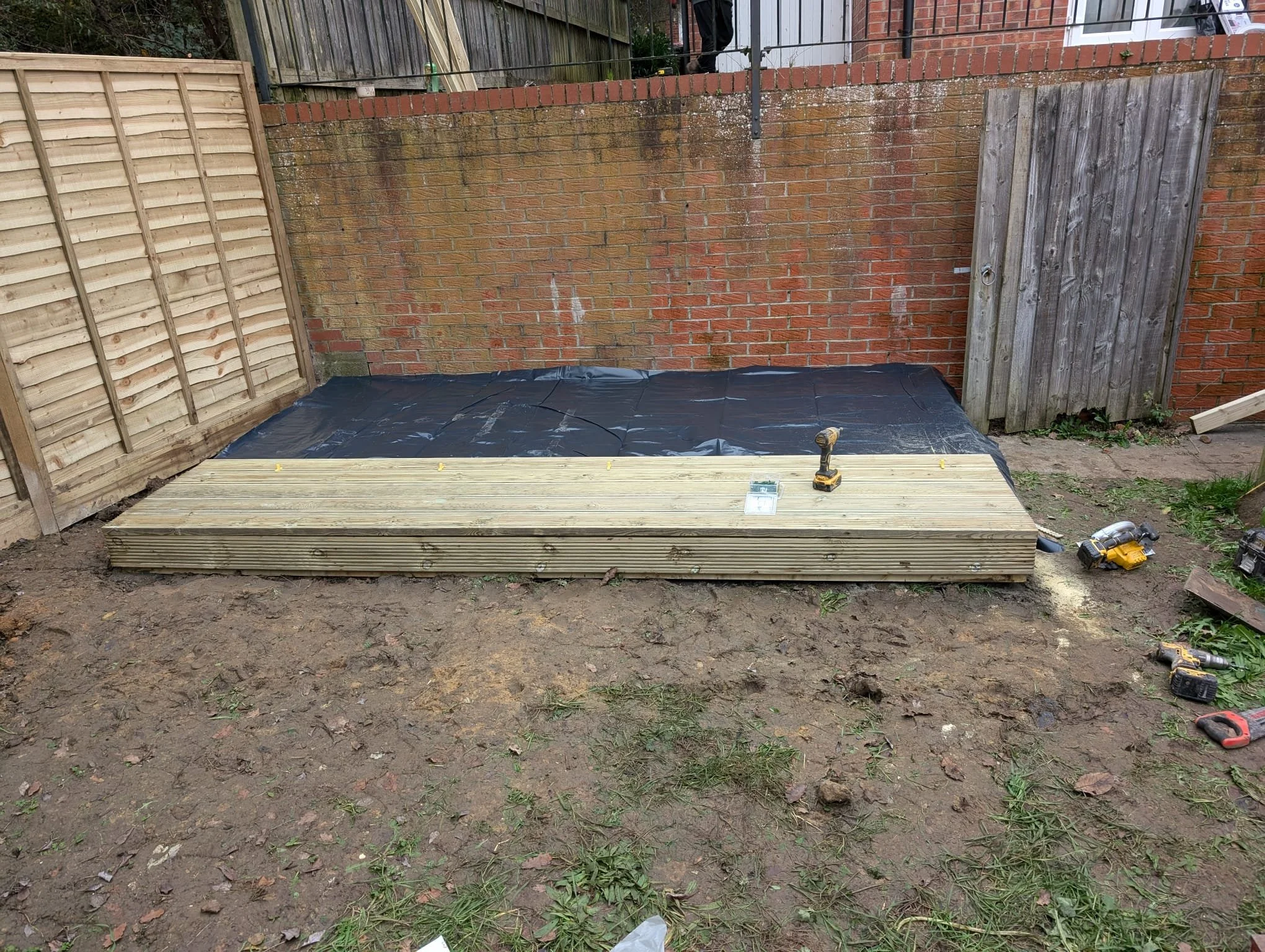 Next came the damp-proof membrane, protecting the timber from moisture and future-proofing the installation. We also used this time to apply a protective paint layer to the fences to prevent weathering. With the first decking boards going down, the
