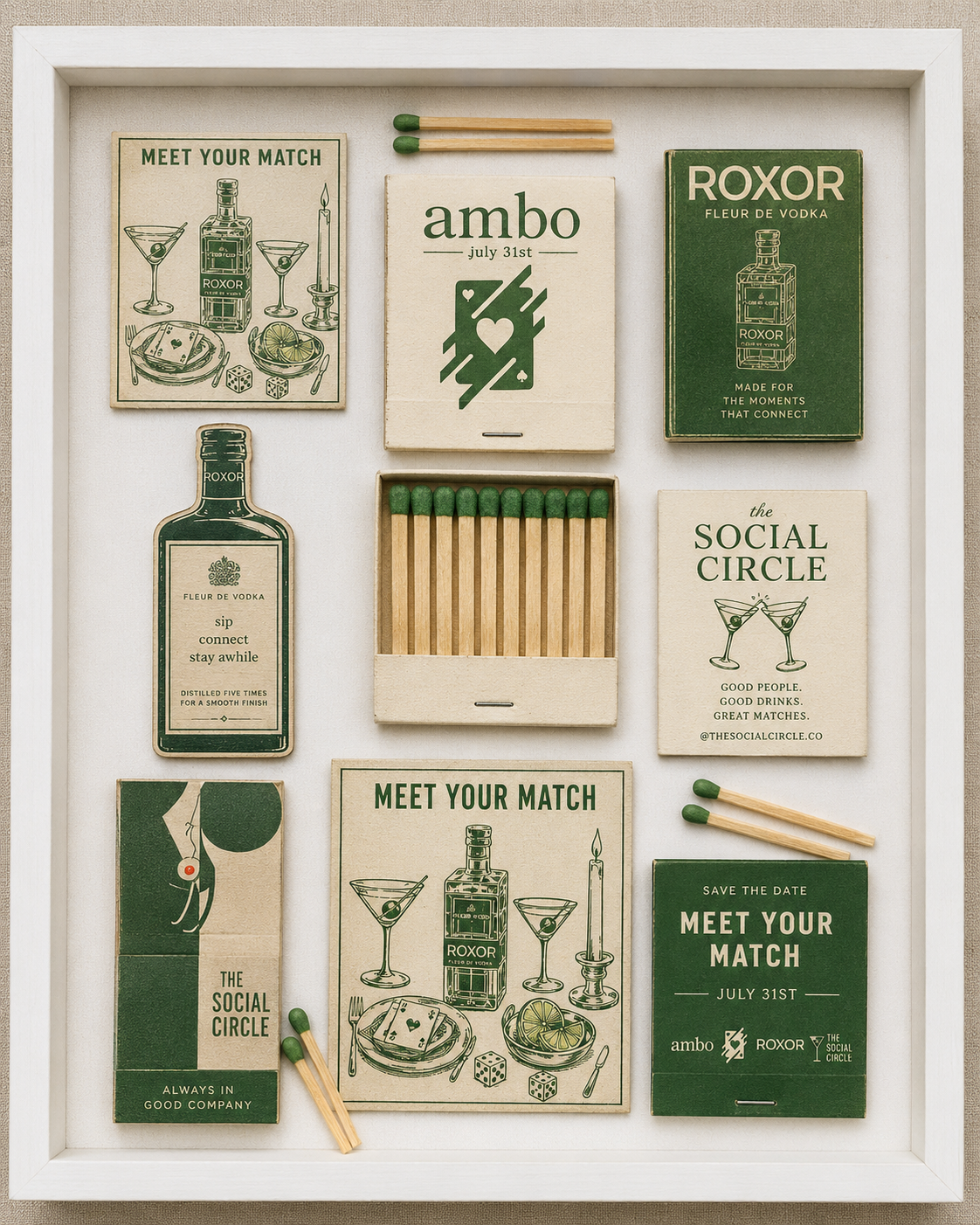 A shadow box display containing matchbooks, matches, and cards with various designs and sayings, all themed around socializing and cocktails, with a white frame and light background.