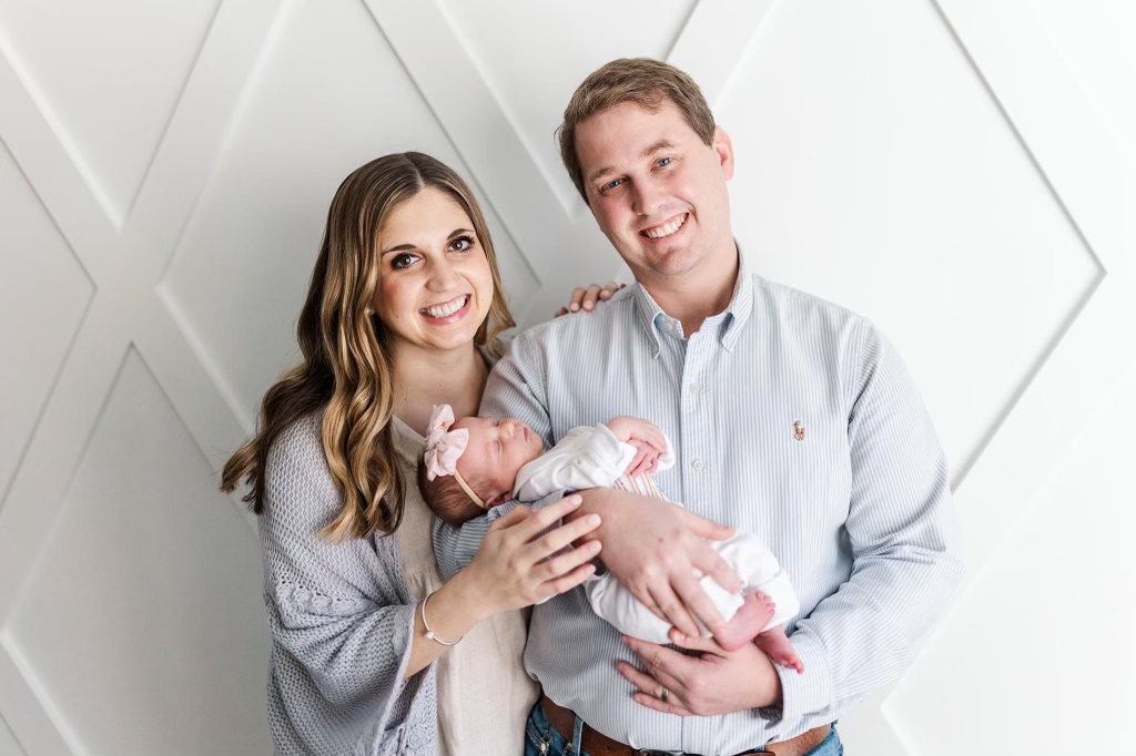 A happy young couple smiling while holding their infant. (Copy)