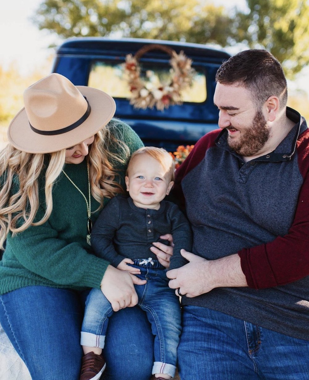 A happy young couple smiling while holding their toddler. (Copy)