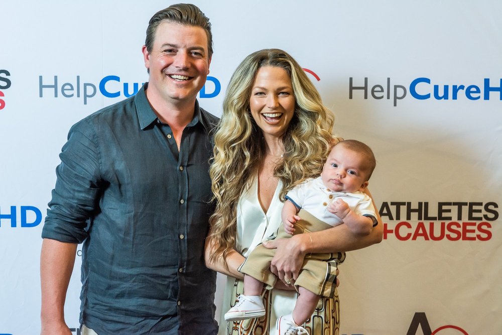 A happy young couple smiling while holding their infant for a picture. (Copy)