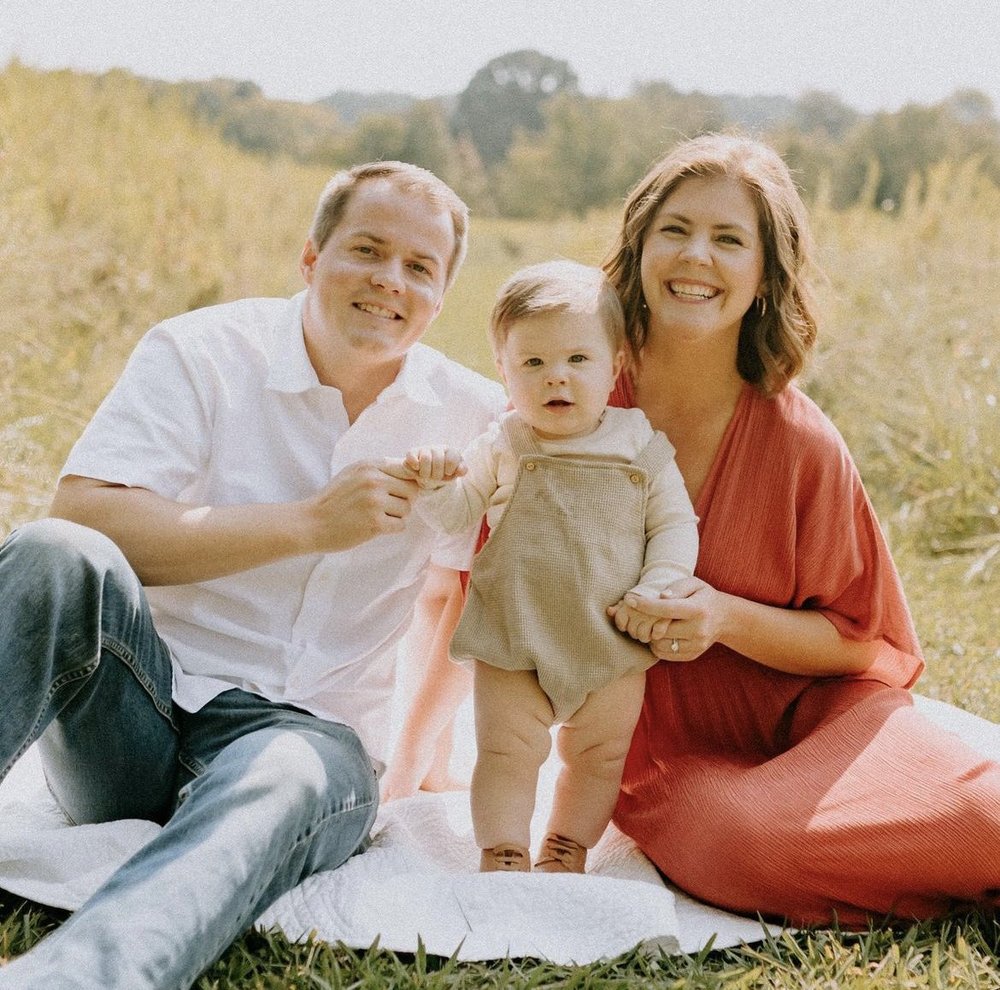 A happy young couple smiling while holding their infant. (Copy)