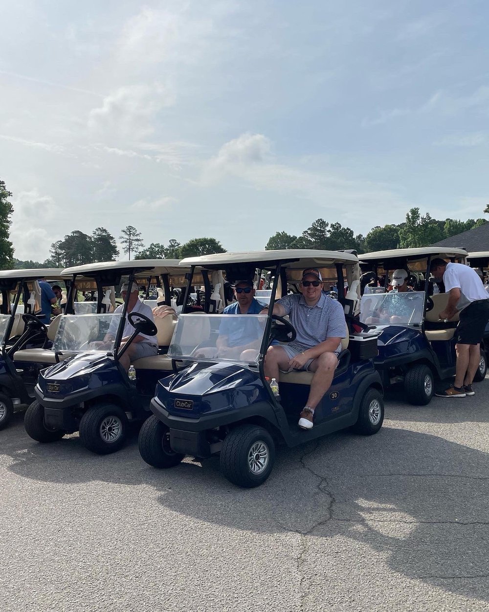 A group of people sitting in golf carts and smiling. (Copy)