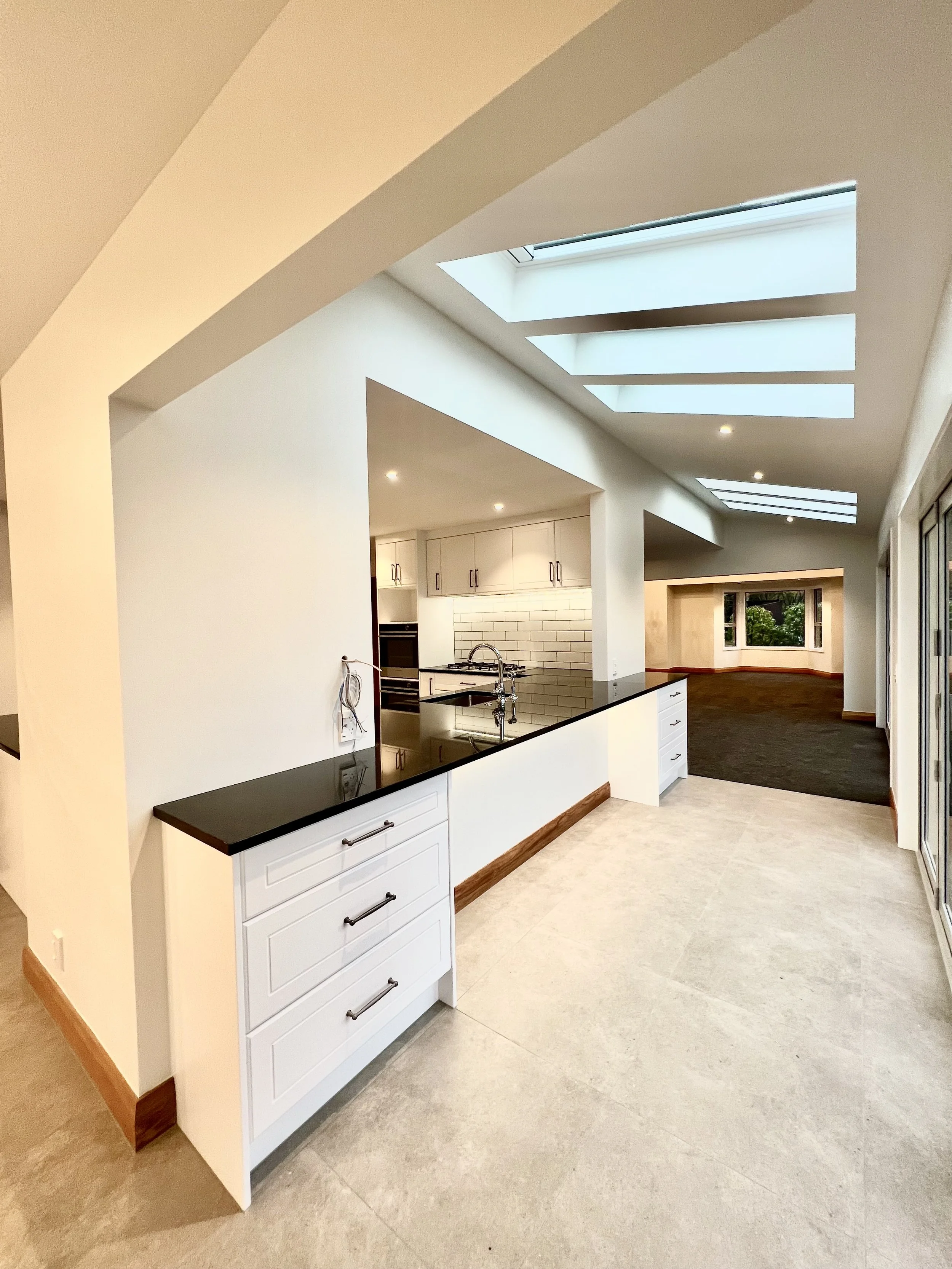 A modern kitchen renovation in Whitby with a stone countertops, LED accent lighting, subway tile and skylights in the ceiling.