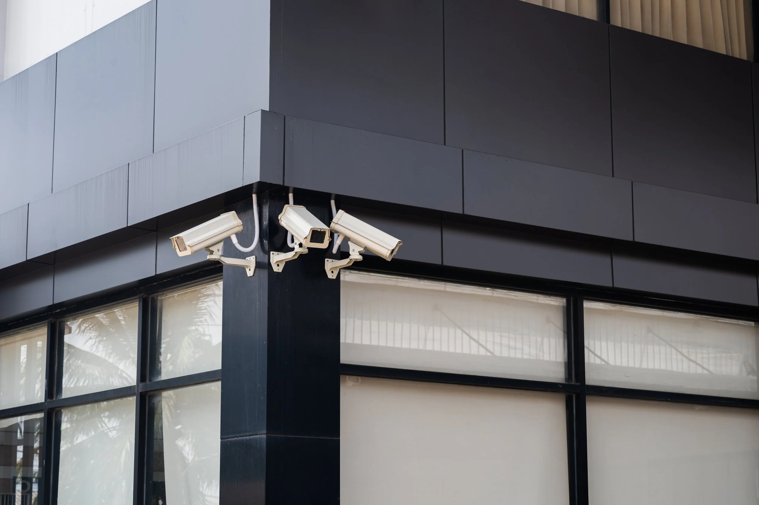 3 security cameras facing different directions outside an office building 