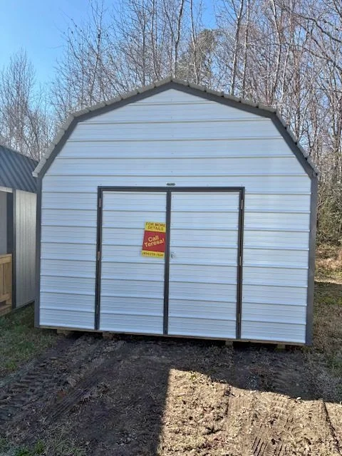 Light blue metal storage shed with double doors, located outdoors with trees in the background and a yellow sign on the door.