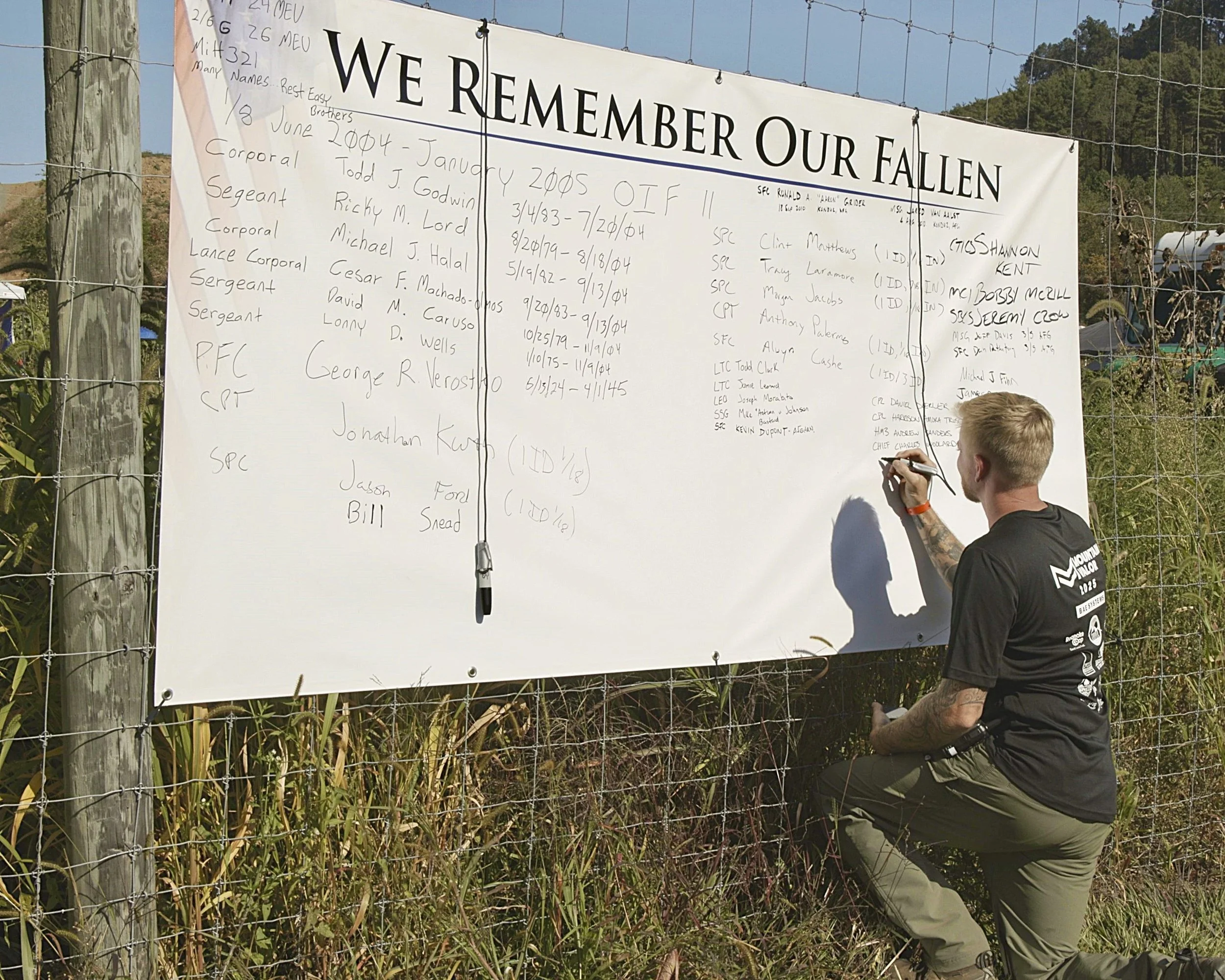 Marine writes the names of the fallen on a remembrance banner.