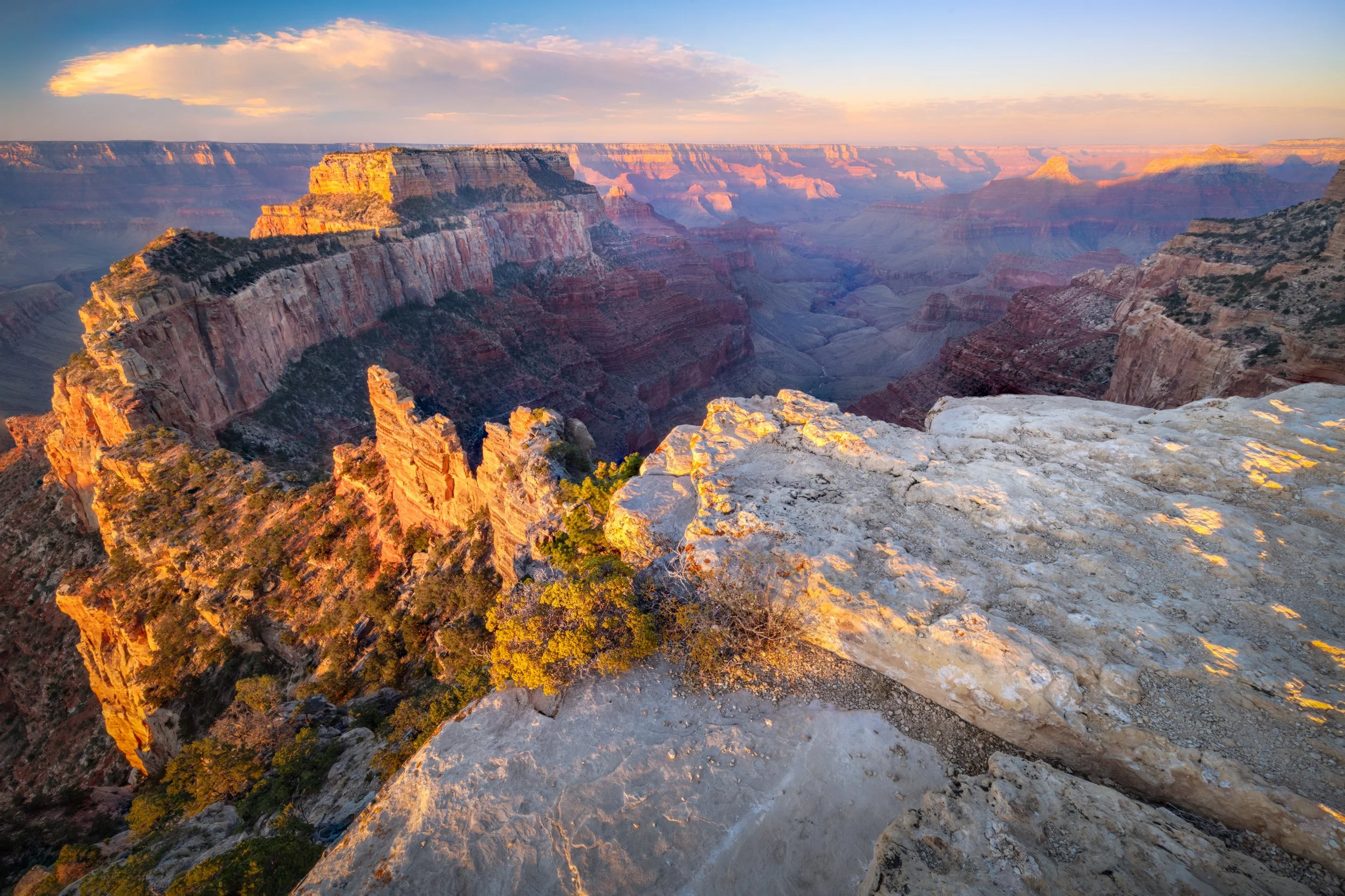 View of the Grand Canyon during sunset showing layered rock formations and a Sky with clouds