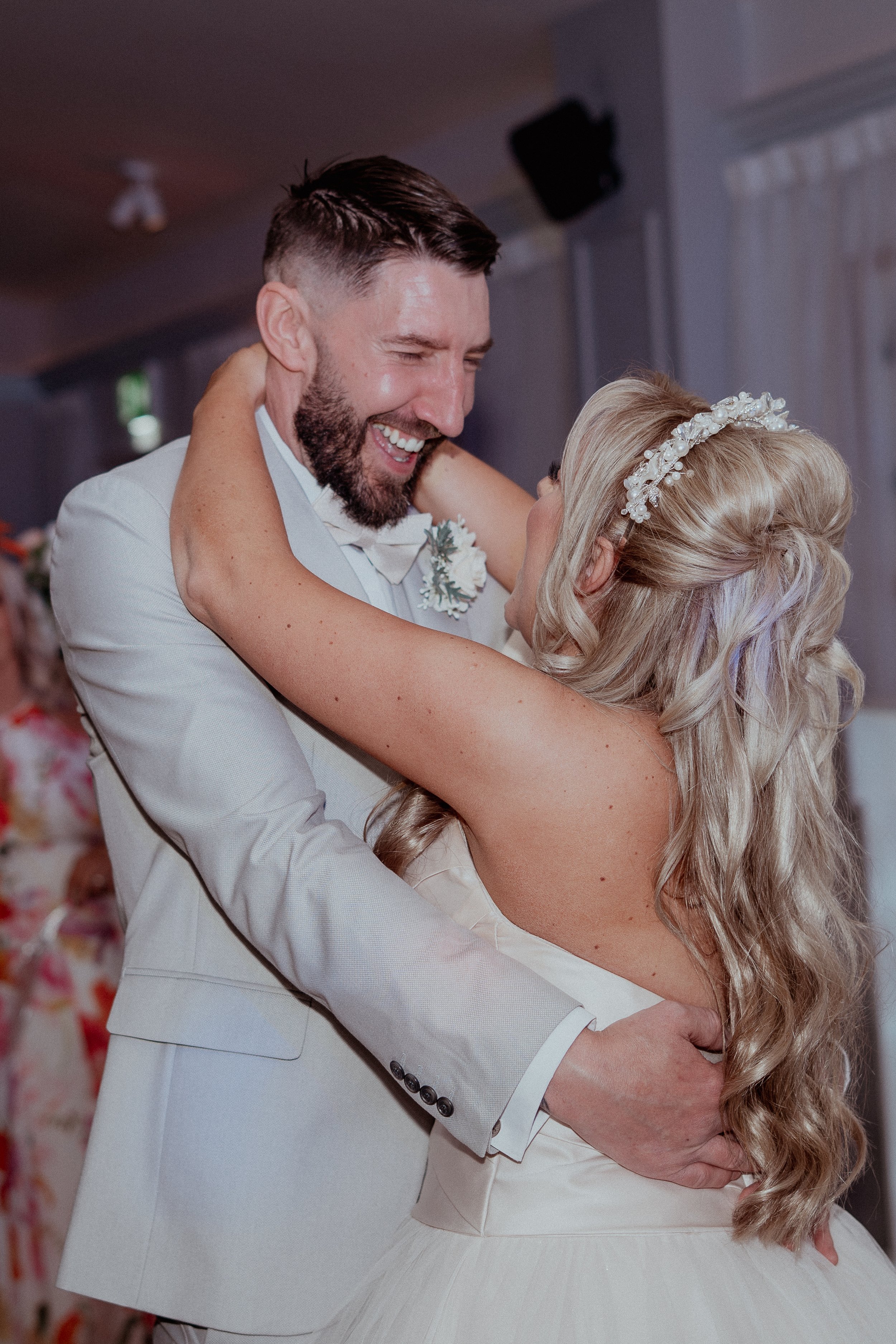 A bride and groom dancing at their wedding, embracing and smiling happily.