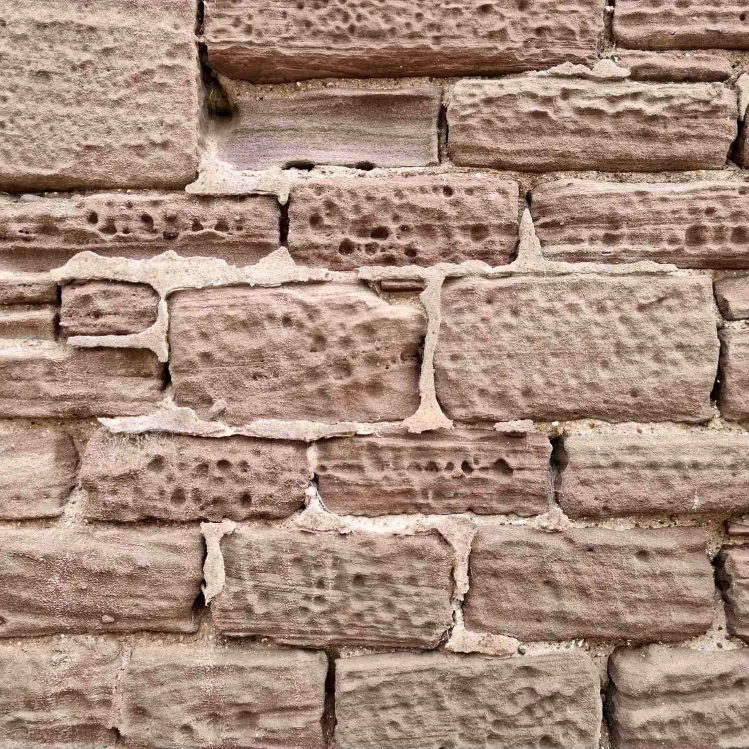 Close-up view of a rubble wall with reddish-brown stone and light-colored mortar.