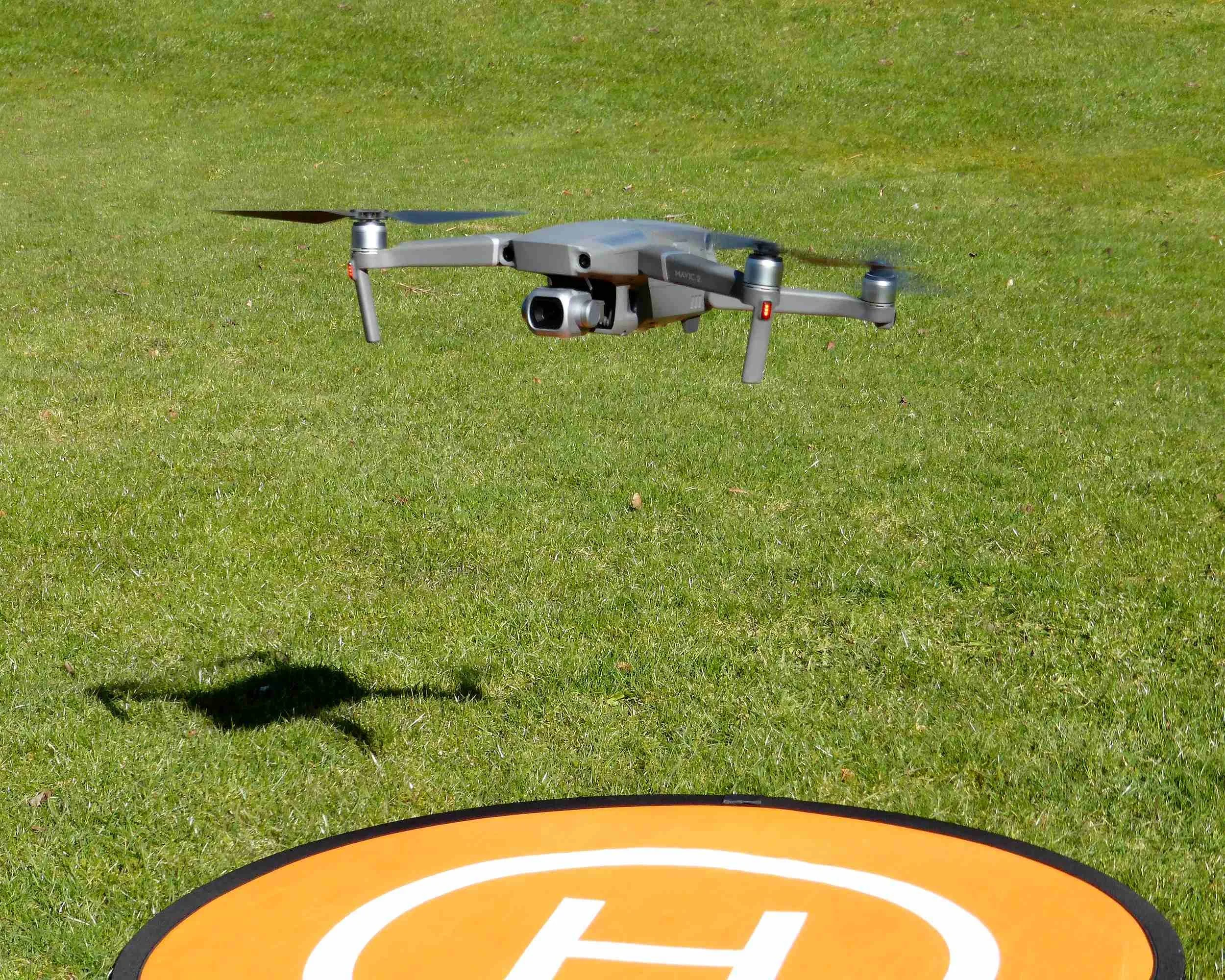 Multirotor drone hovering over landing pad