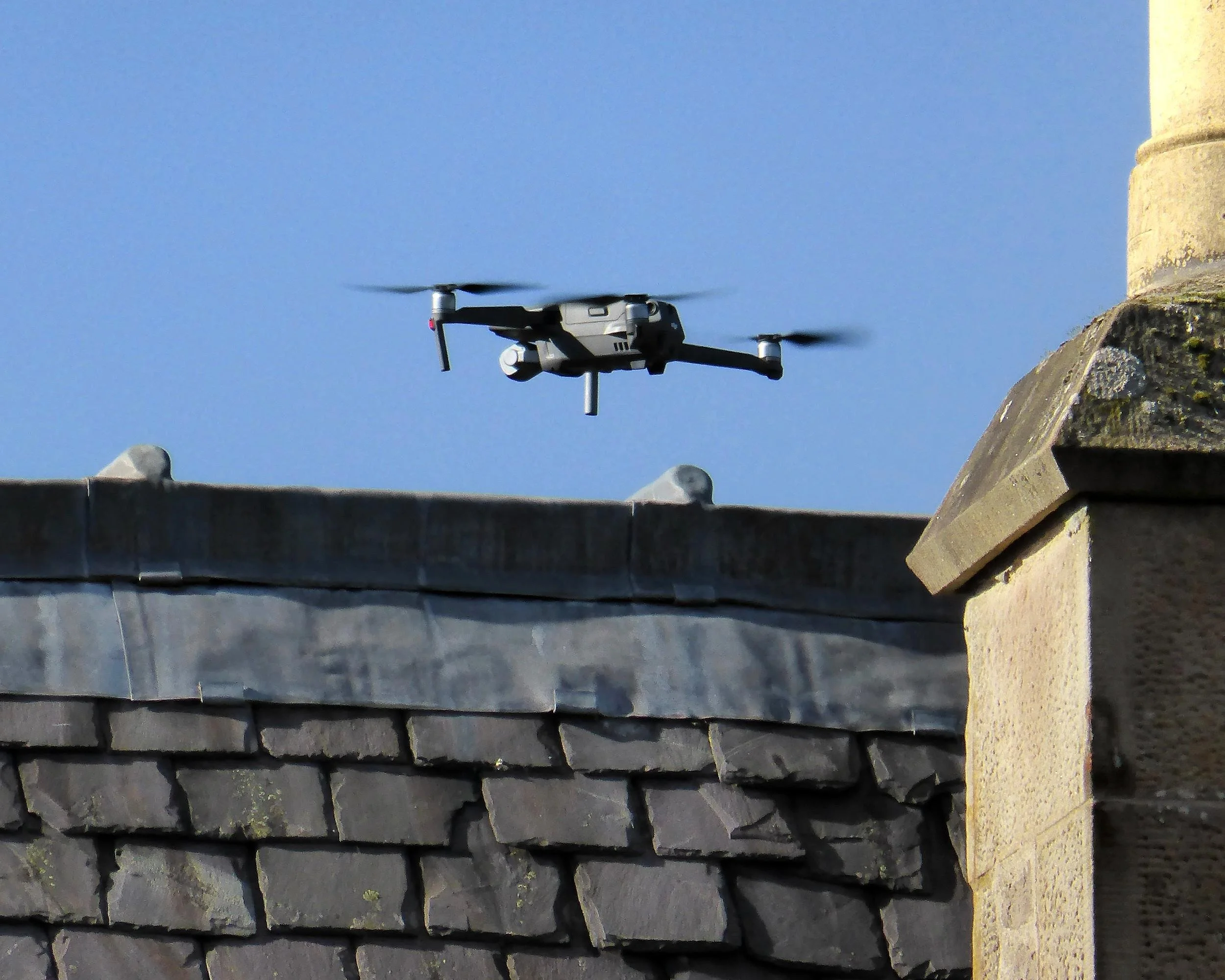 Drone hovering over a slate roof and chimney