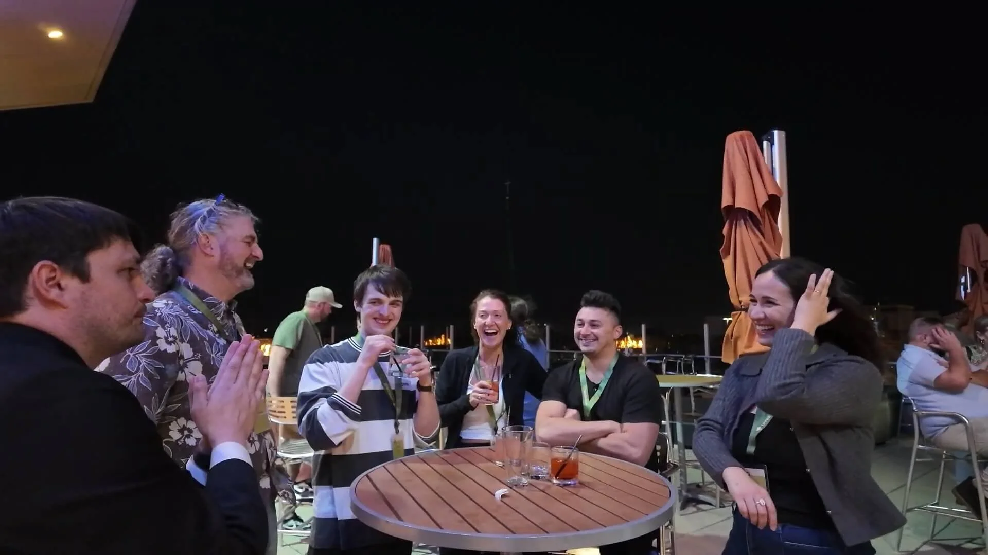Strolling magician Josh Weidner performing close-up card magic for laughing guests at a corporate cocktail hour