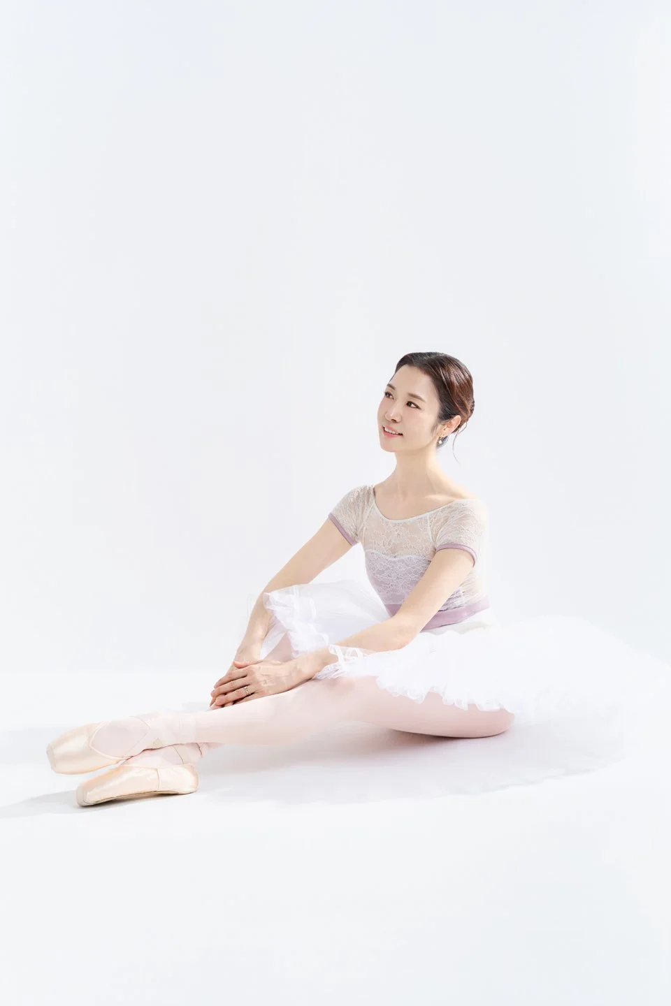 Julie seated in a white tutu for a ballet portrait.