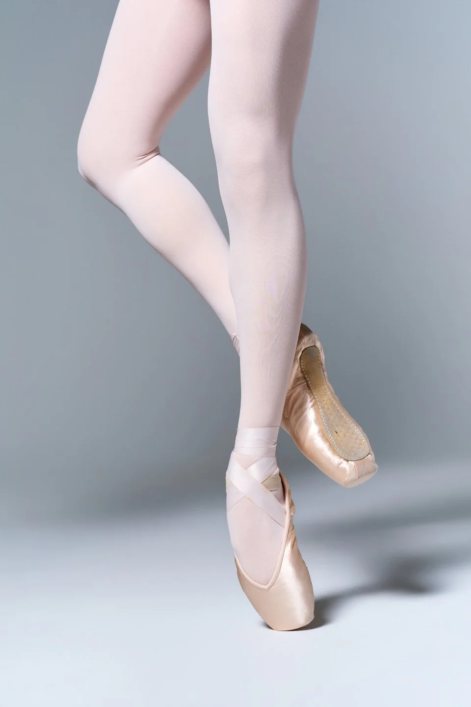 Detail of Julie’s pointe shoes and ballet pose against a gray studio backdrop.
