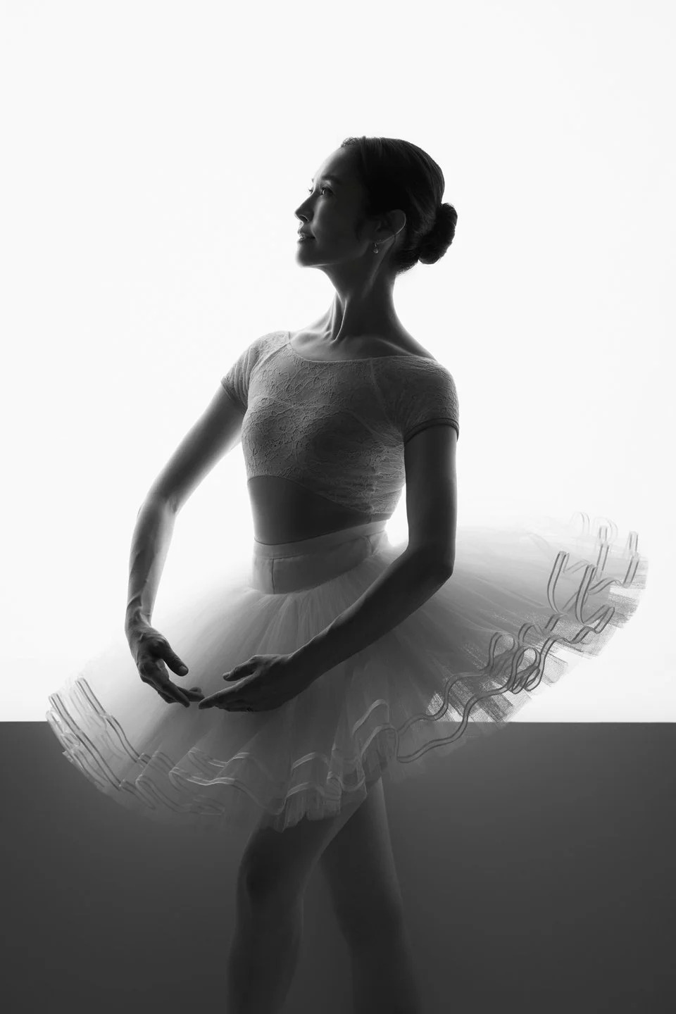 Black-and-white portrait of Julie in a tutu with dramatic window light.