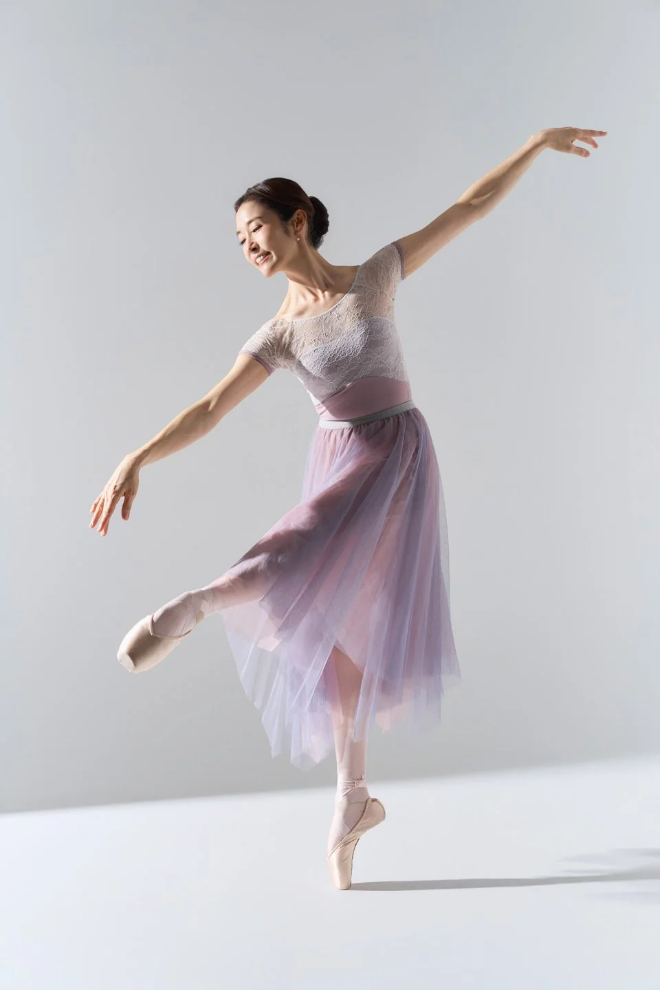 Julie in a graceful ballet pose against a gray studio background.