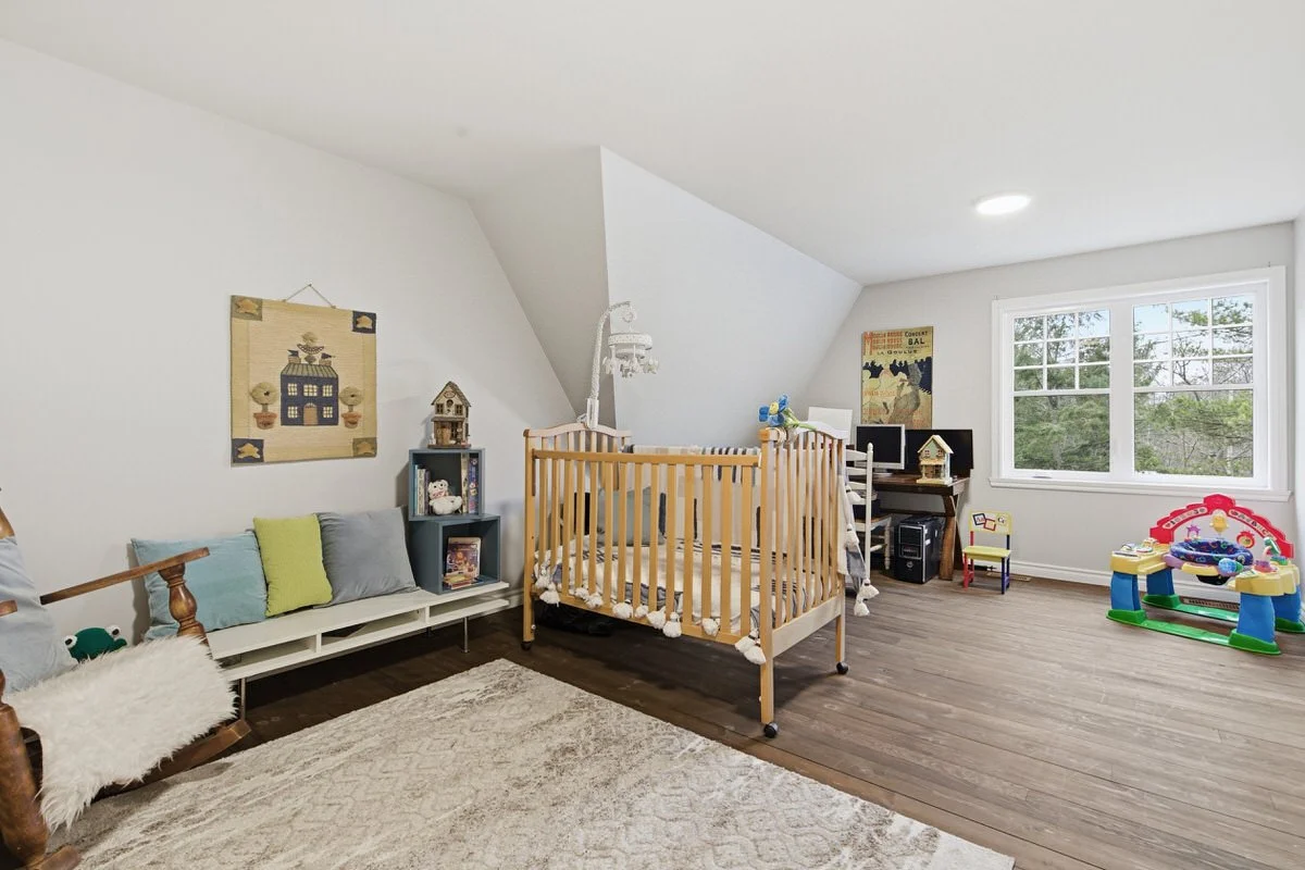 A baby's nursery with a wooden crib, a changing table, a TV and play area, and various decorative items.