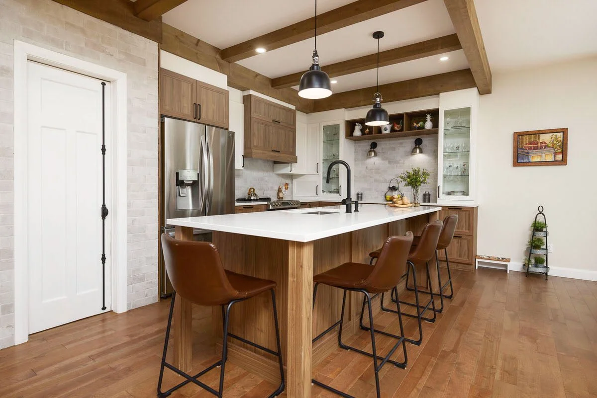 Modern kitchen with wooden cabinets, a white island with bar stools, stainless steel refrigerator, and pendant lighting.