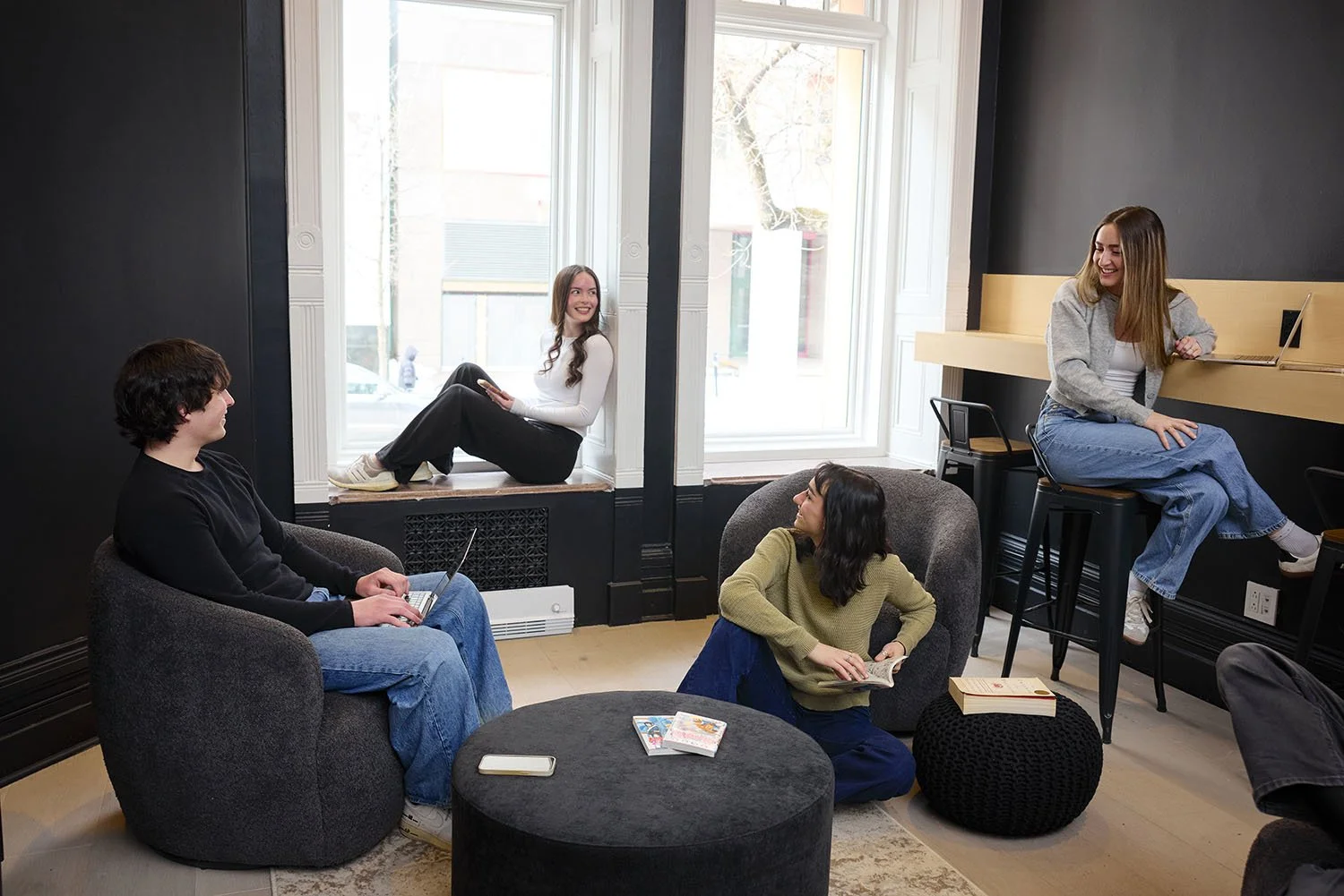 A lifestyle photo of a group of young adults hanging out in the common space of a youth hostel in Montreal.