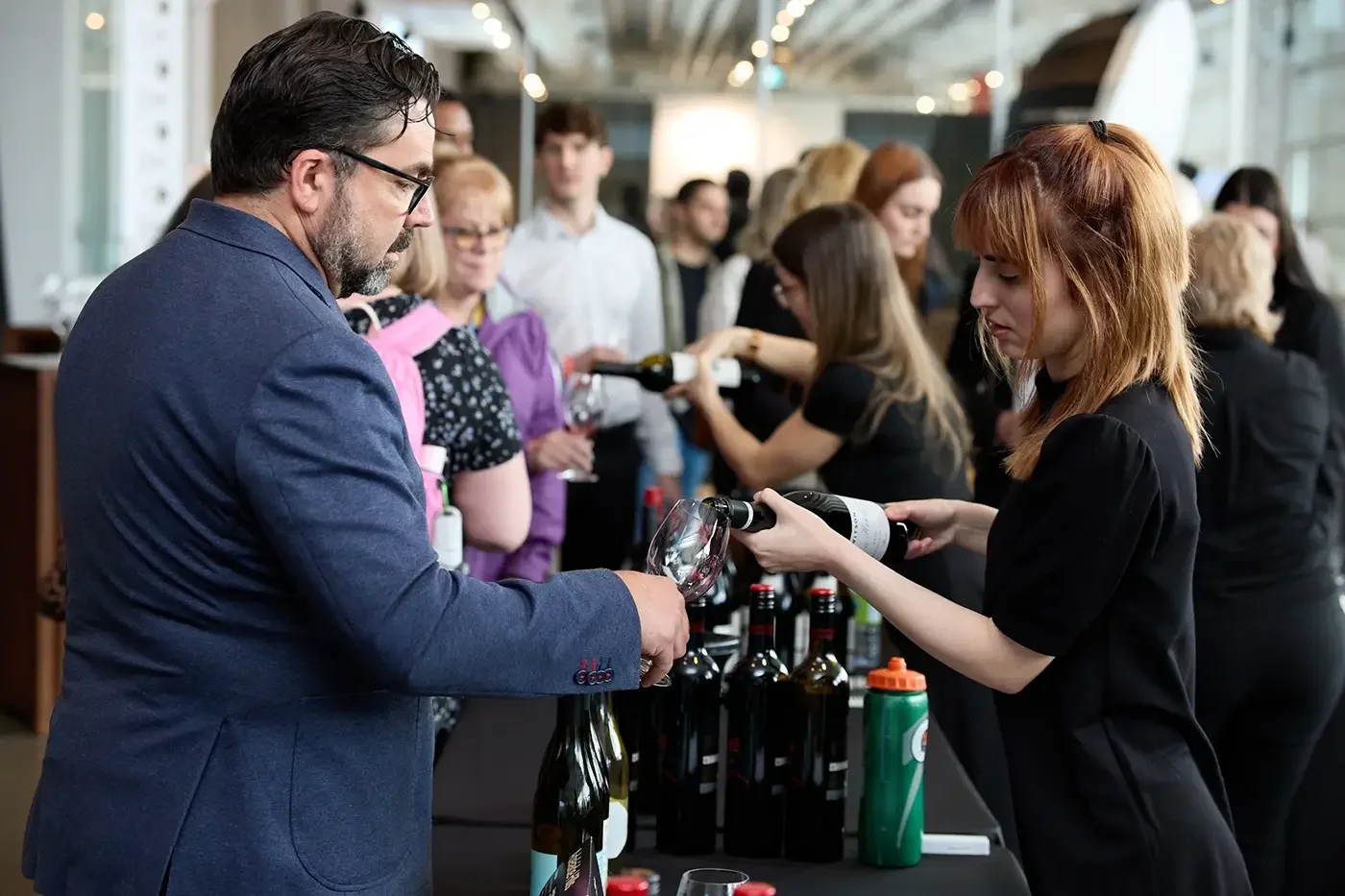 A photo of a sommelier pouring a glass of wine at a corporate trade show event in Montreal.