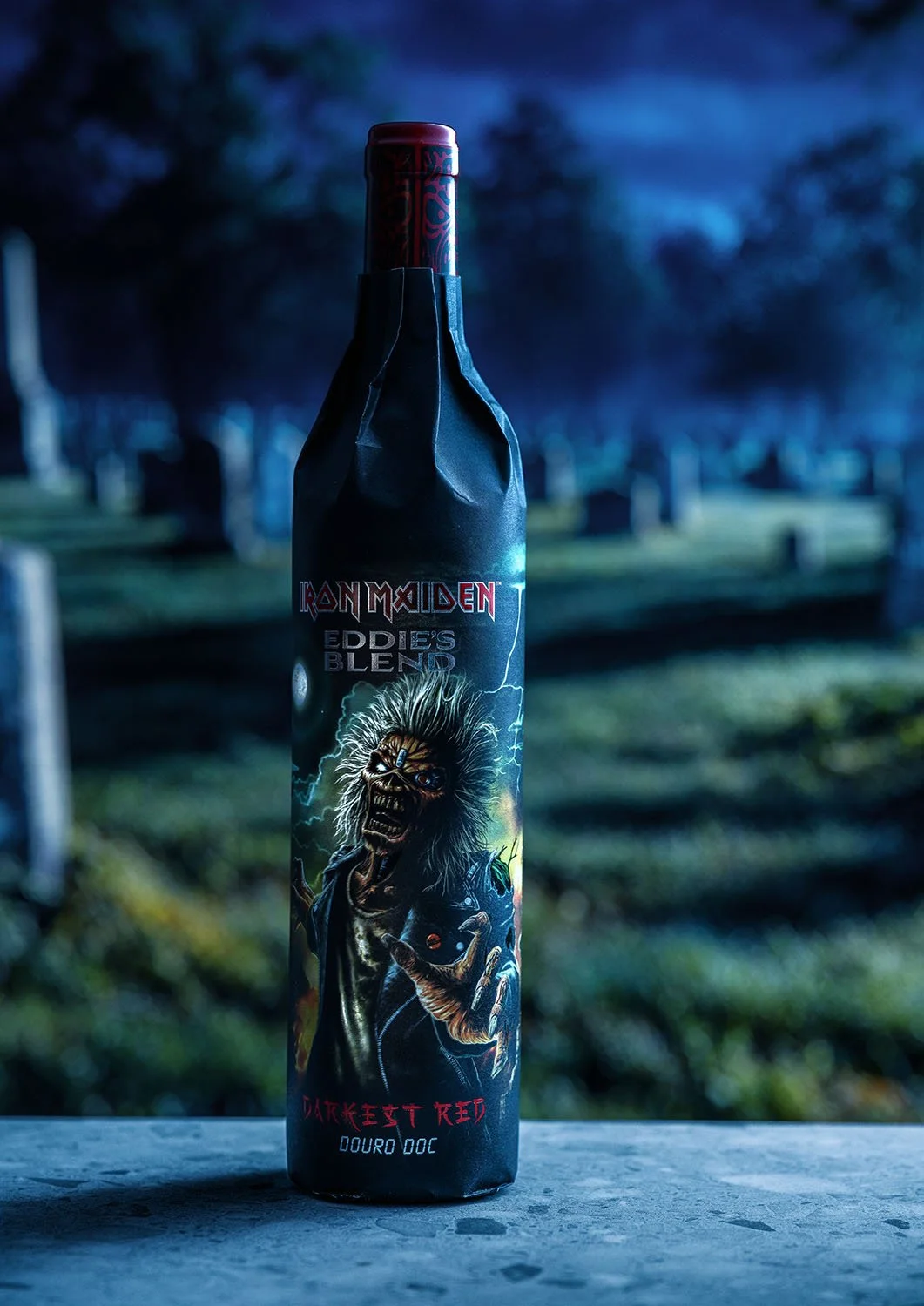 A bottle of Iron Maiden Eddie's Blend wine against a graveyard background at night.