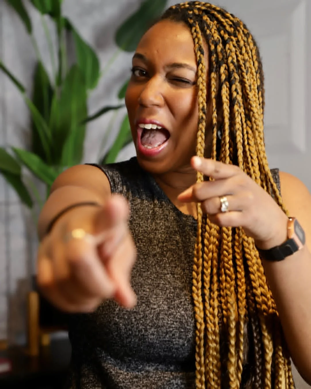 A portrait of a woman winking and pointing at the camera.