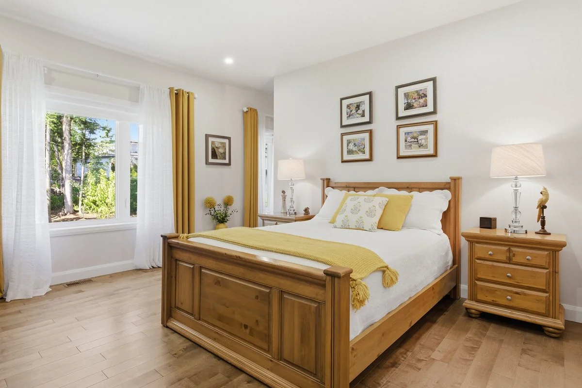 A cozy bedroom with a wooden bed, yellow accents, and artwork on the walls.
