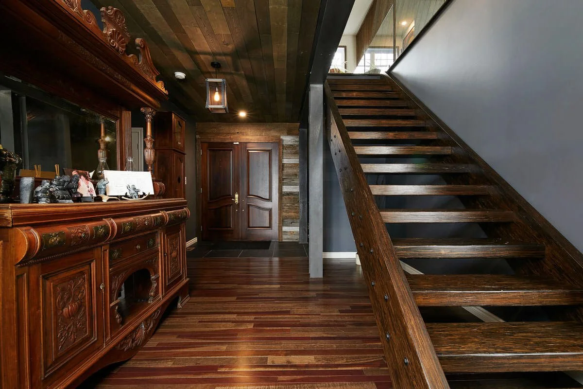 Interior of a house with dark wooden staircase and antique wooden sideboard