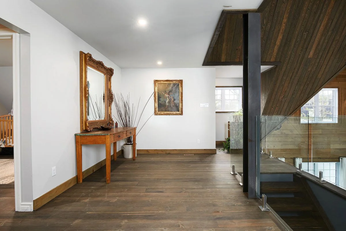 Interior of a modern home with wooden floors, a sailing ship model, and framed artwork.