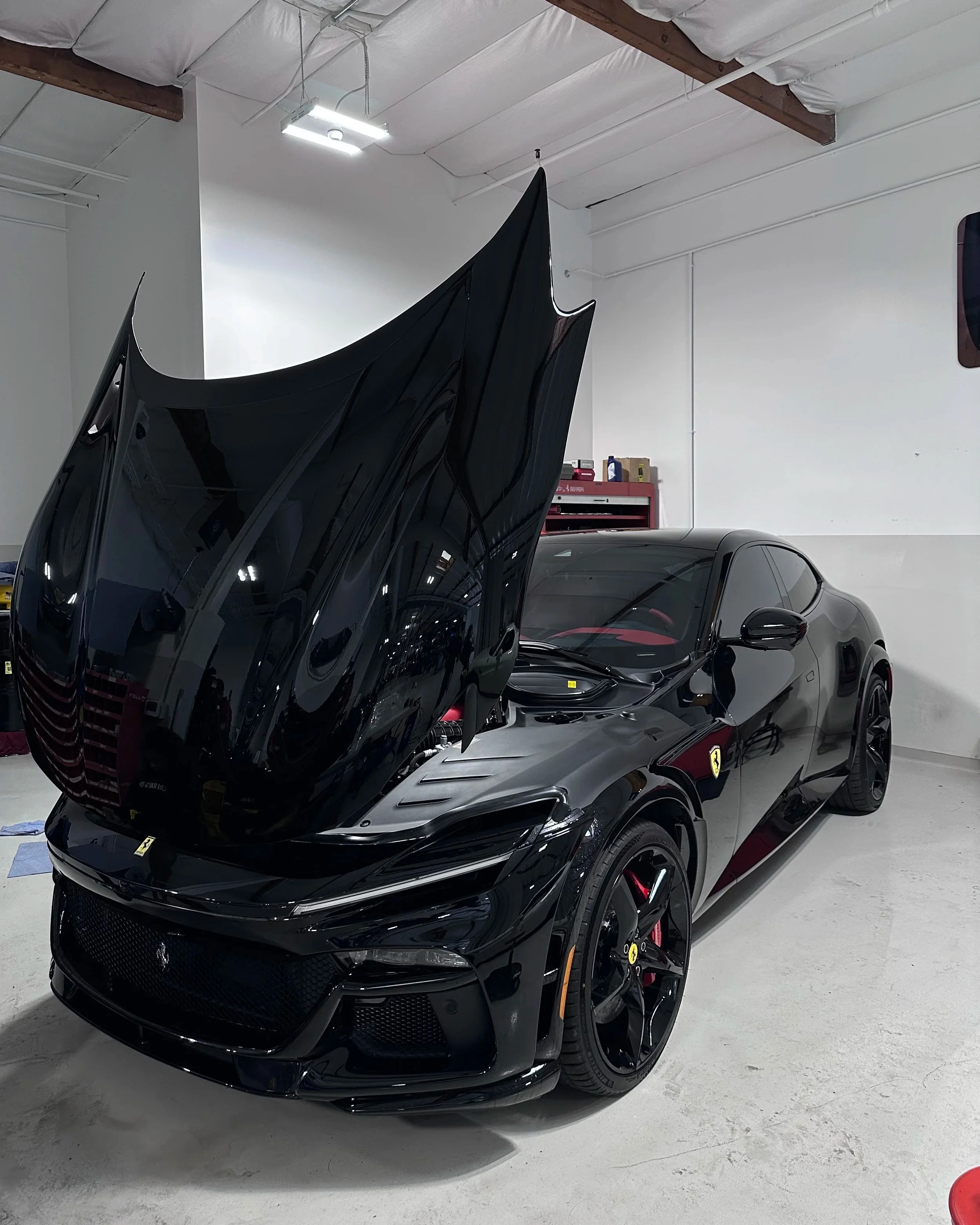 Black sports car receiving paint protection film installation indoors in Walnut Creek CA
