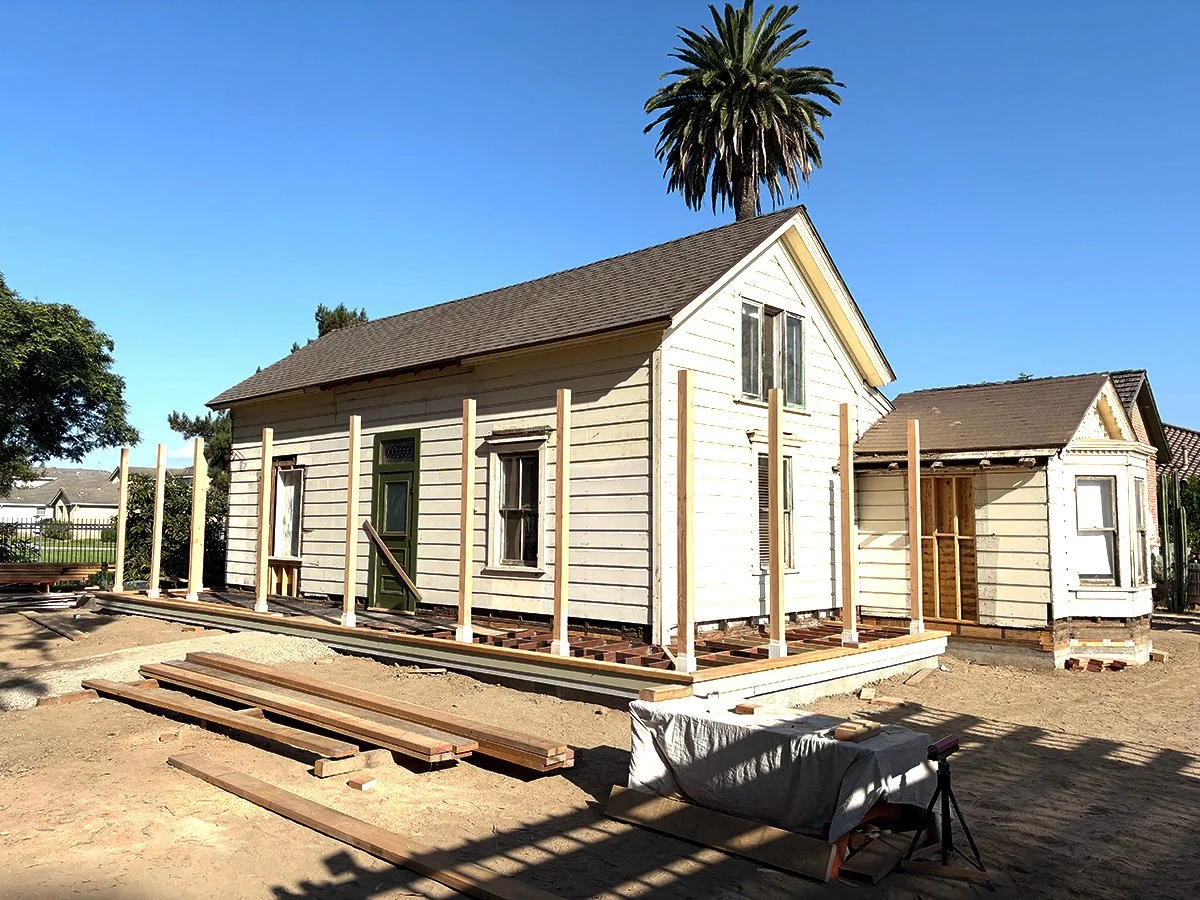 Undergoing house renovation, with wooden framing and construction materials in an outdoor area on a clear day.