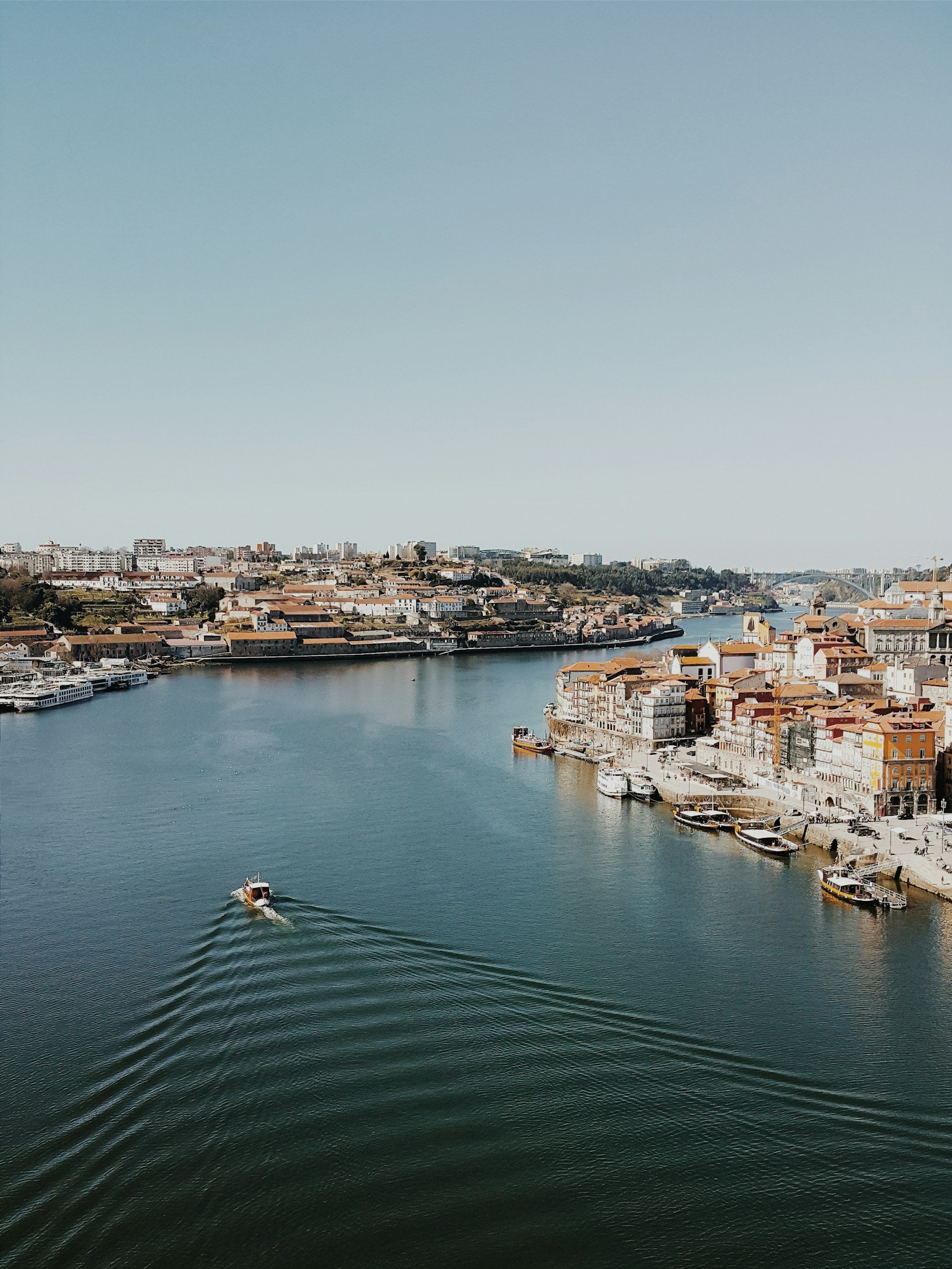 A river in a city with boats and buildings along the waterfront, under a clear sky.