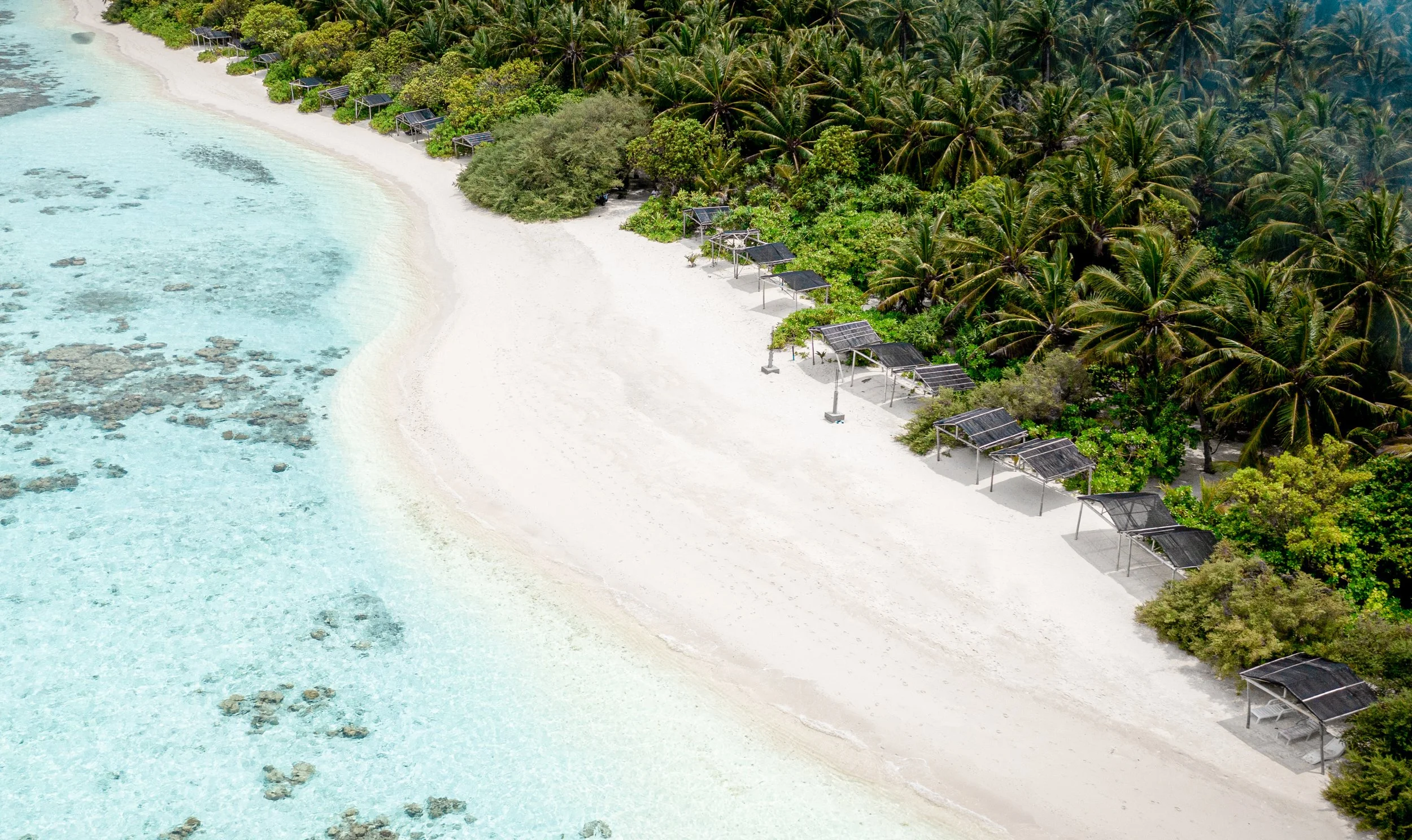Sunset over the ocean with a thatched-roof hut in the foreground