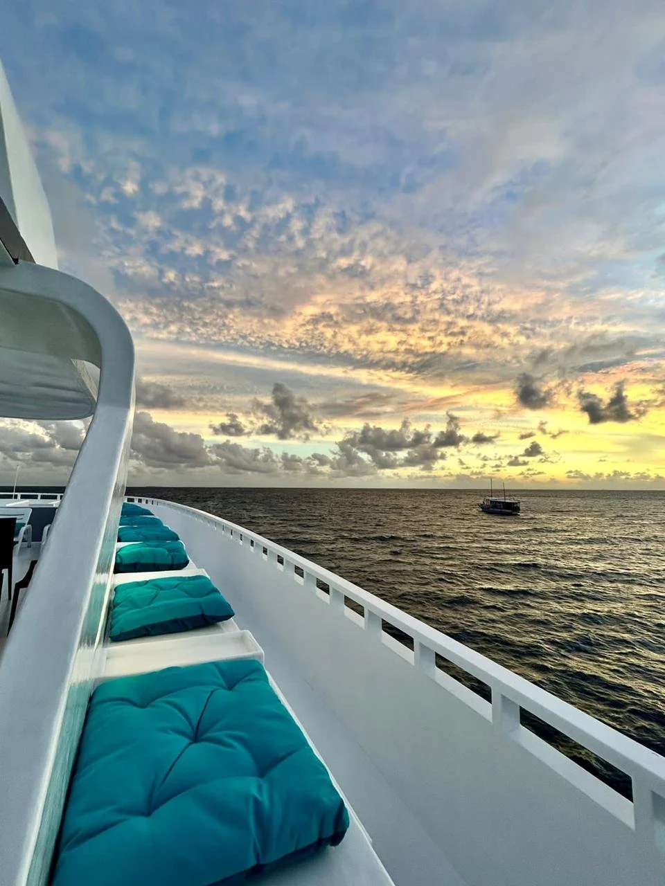Silhouette of a boat on water during sunset with mountainous landscape in the background.