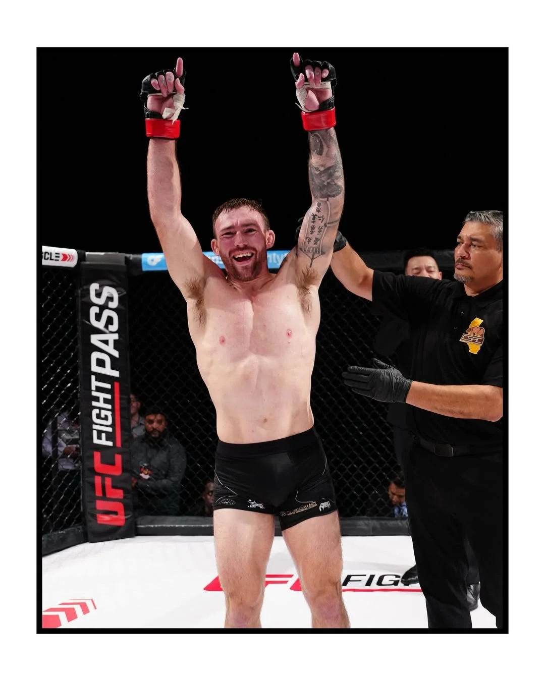 A man in a dark gym is lifting a barbell with weights, crouching down with a focused posture.