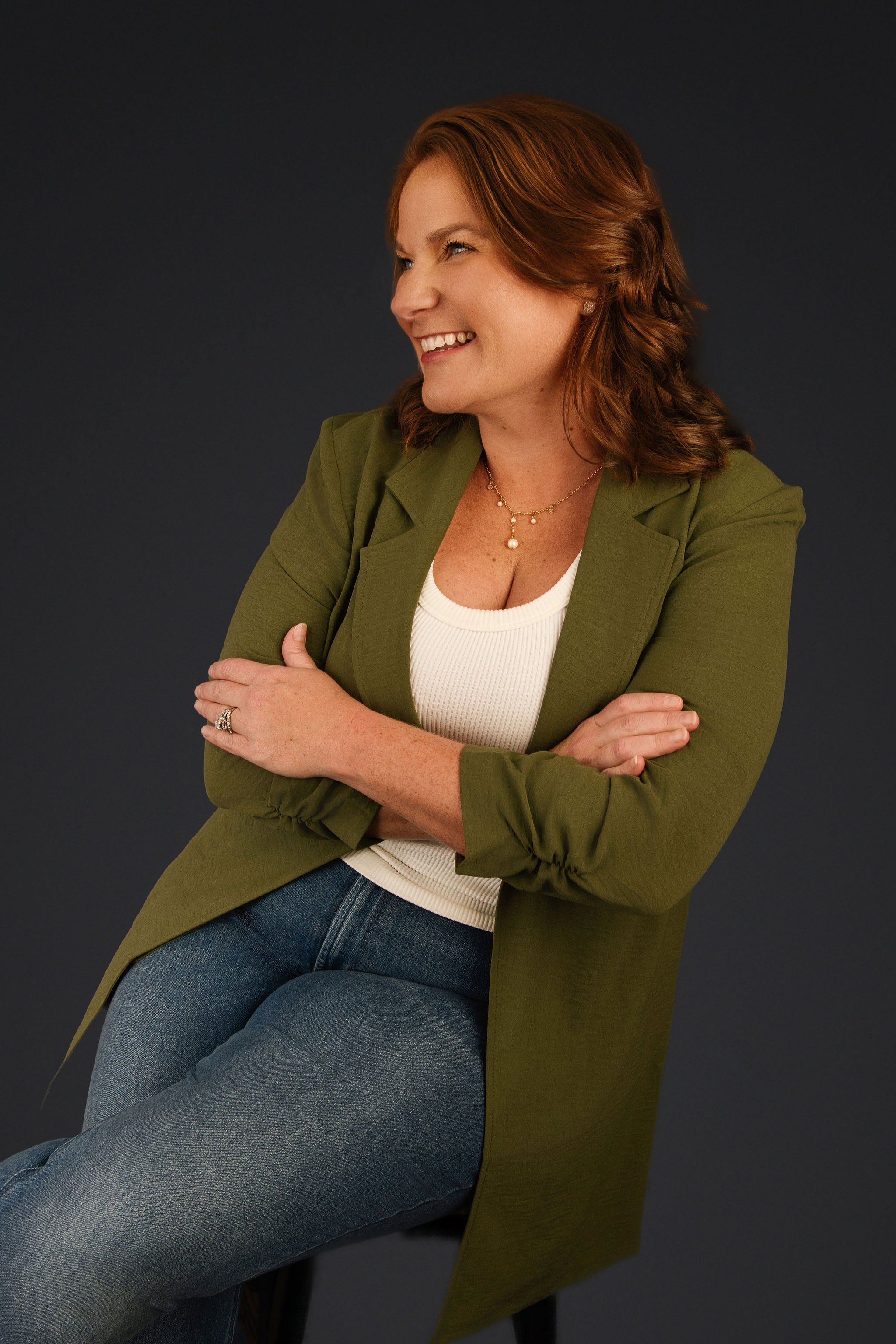 Jessica looking off camera with a smile, sitting on a stool with arms crossed. happy :)