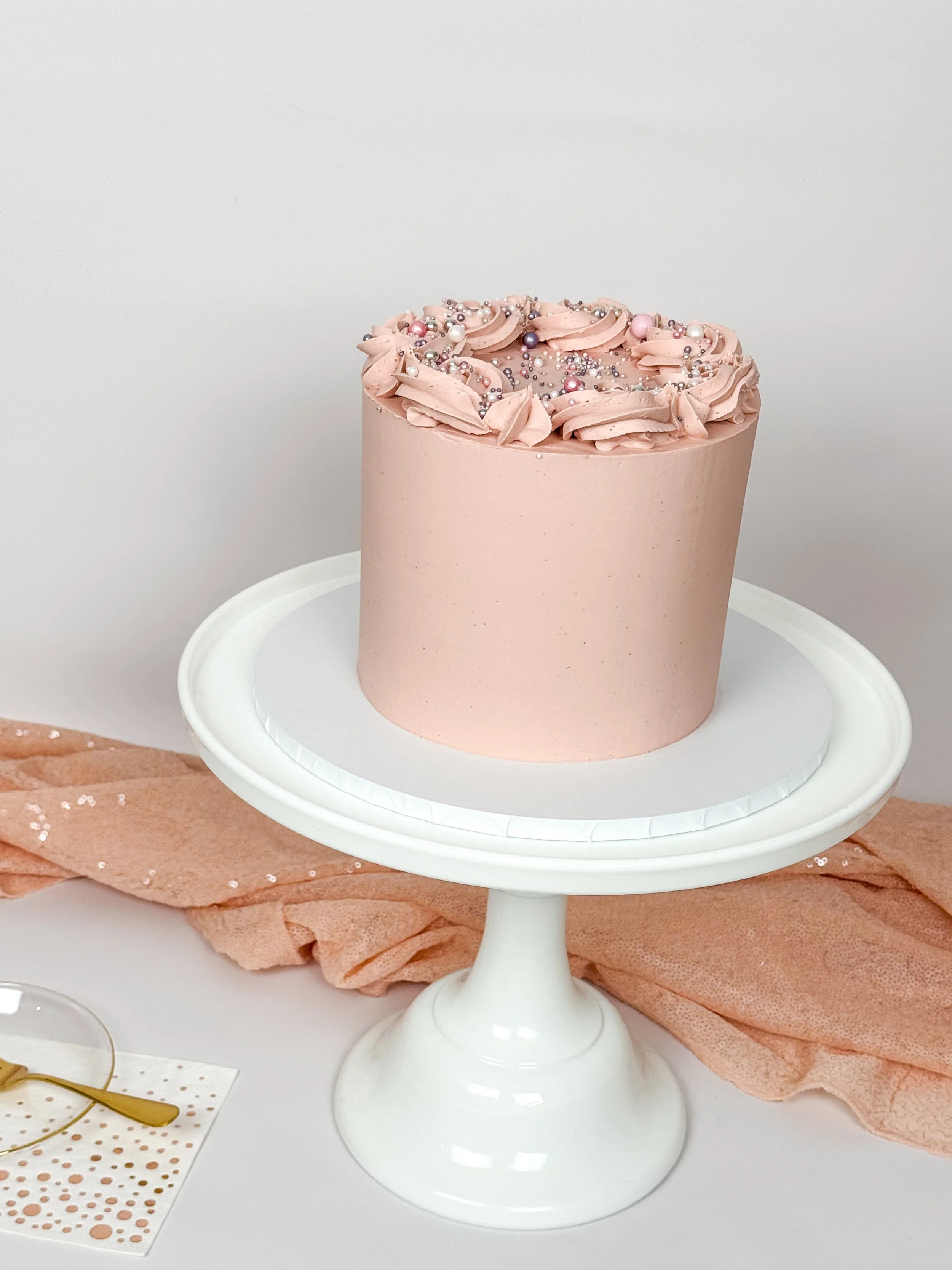 Decorated cake on cake stand with sequin table coth, dessert plate and fork