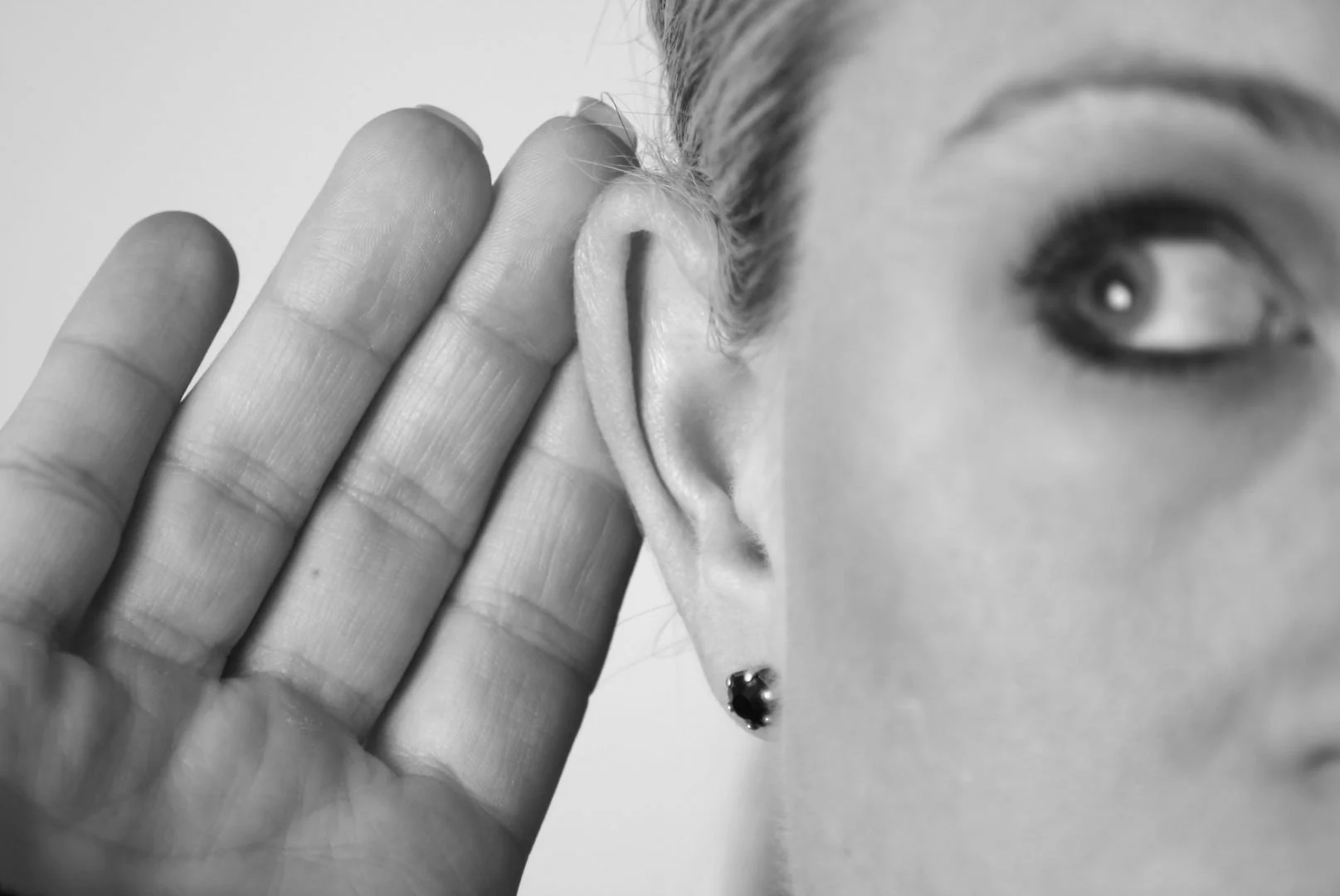 A woman cupping her ear to listen.