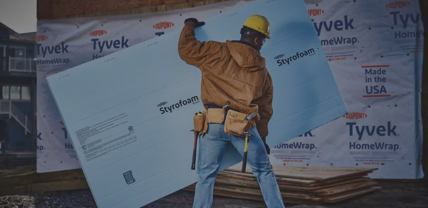 A professional carries a DOW STYROFOAM™ insulation board on a job site.